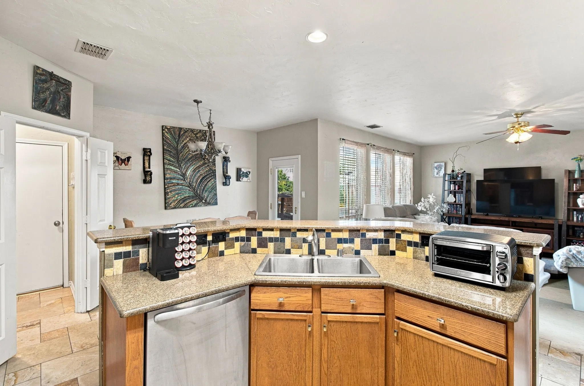 Kitchen featuring a double basin stainless steel sink, wood cabinetry, and a tile backsplash
