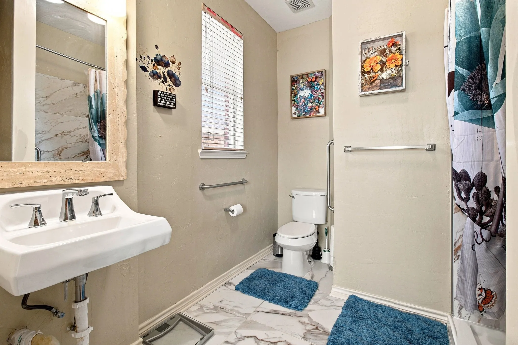 Pedestal sink with chrome fixtures, white toilet, grab bar, and a window with blinds