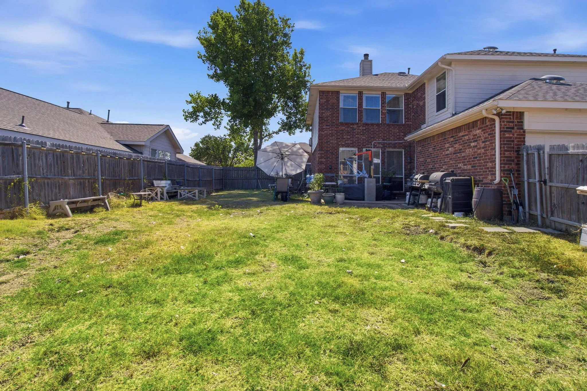Expansive grassy yard with mature trees and a privacy fence