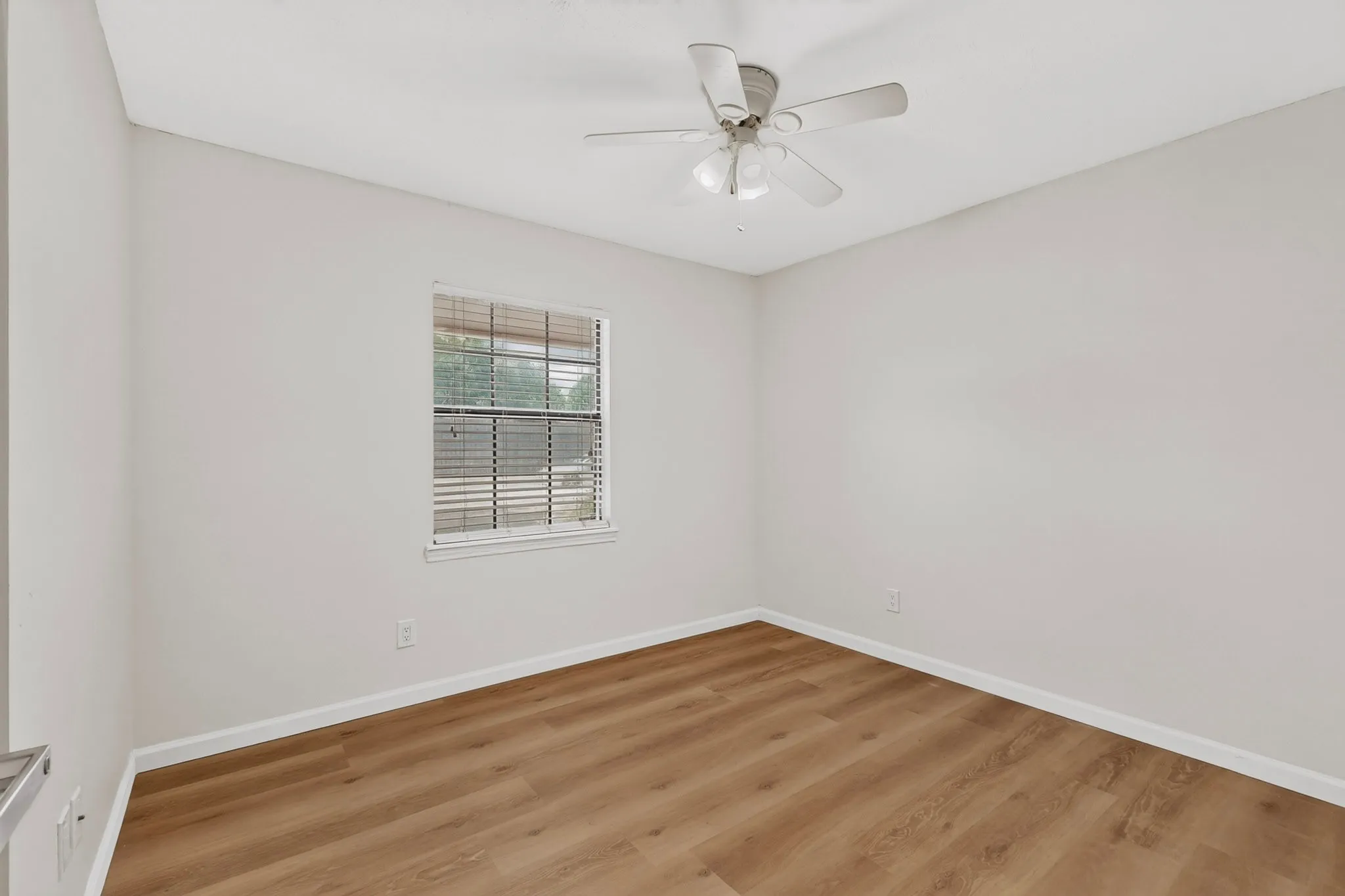 Wood-finish flooring, white walls, window with blinds, and a ceiling fan