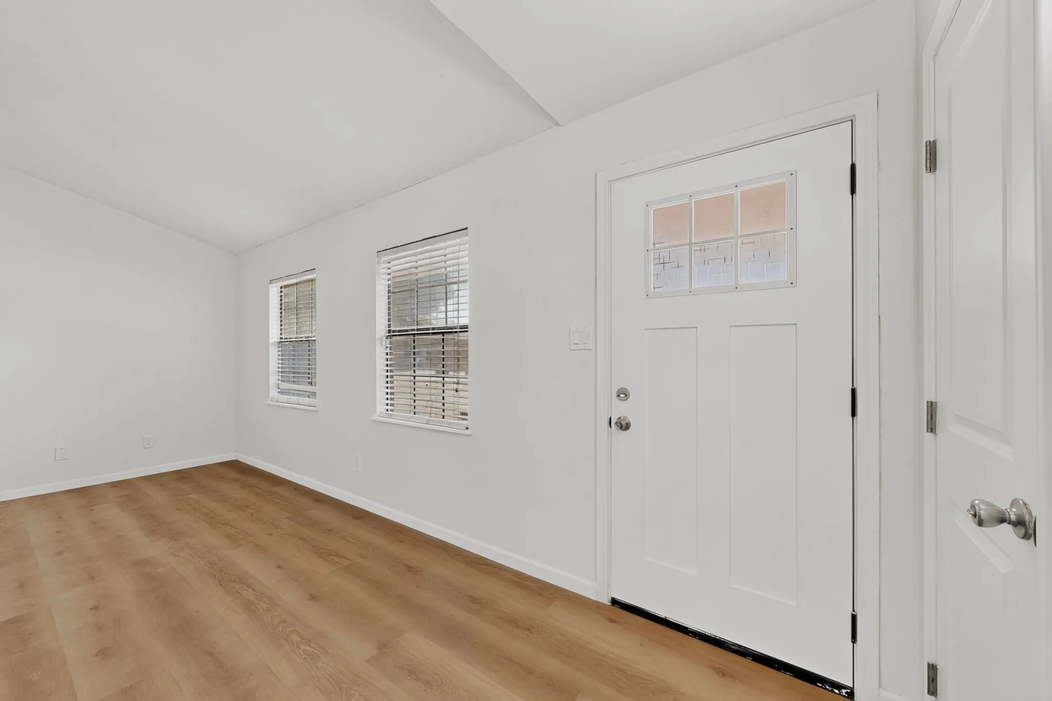 Wood-finish flooring, white paneled door with divided lite glass, and white walls