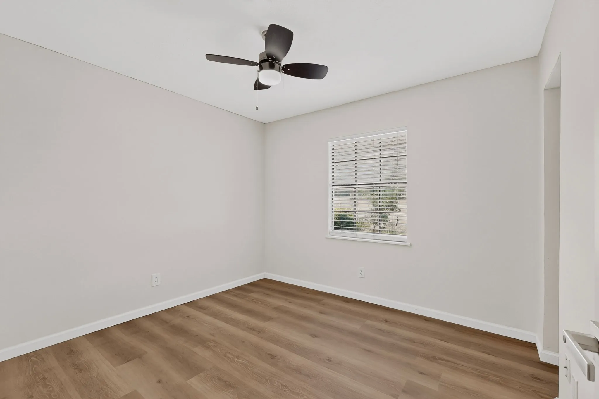 Neutral wall paint, wood-finish flooring, and a ceiling fan with integrated lighting