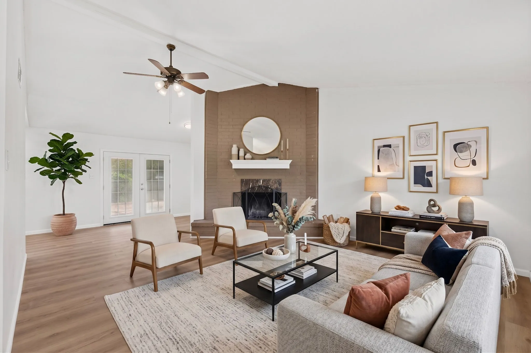 Vaulted ceiling with a ceiling fan, brick fireplace with a mantel, wood-finish flooring, and double glass-paneled doors