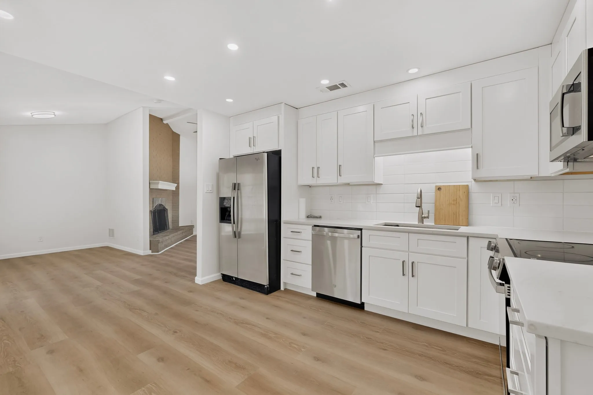Modern kitchen featuring white shaker cabinetry, stainless steel appliances, light-toned countertops, and a subway tile backsplash