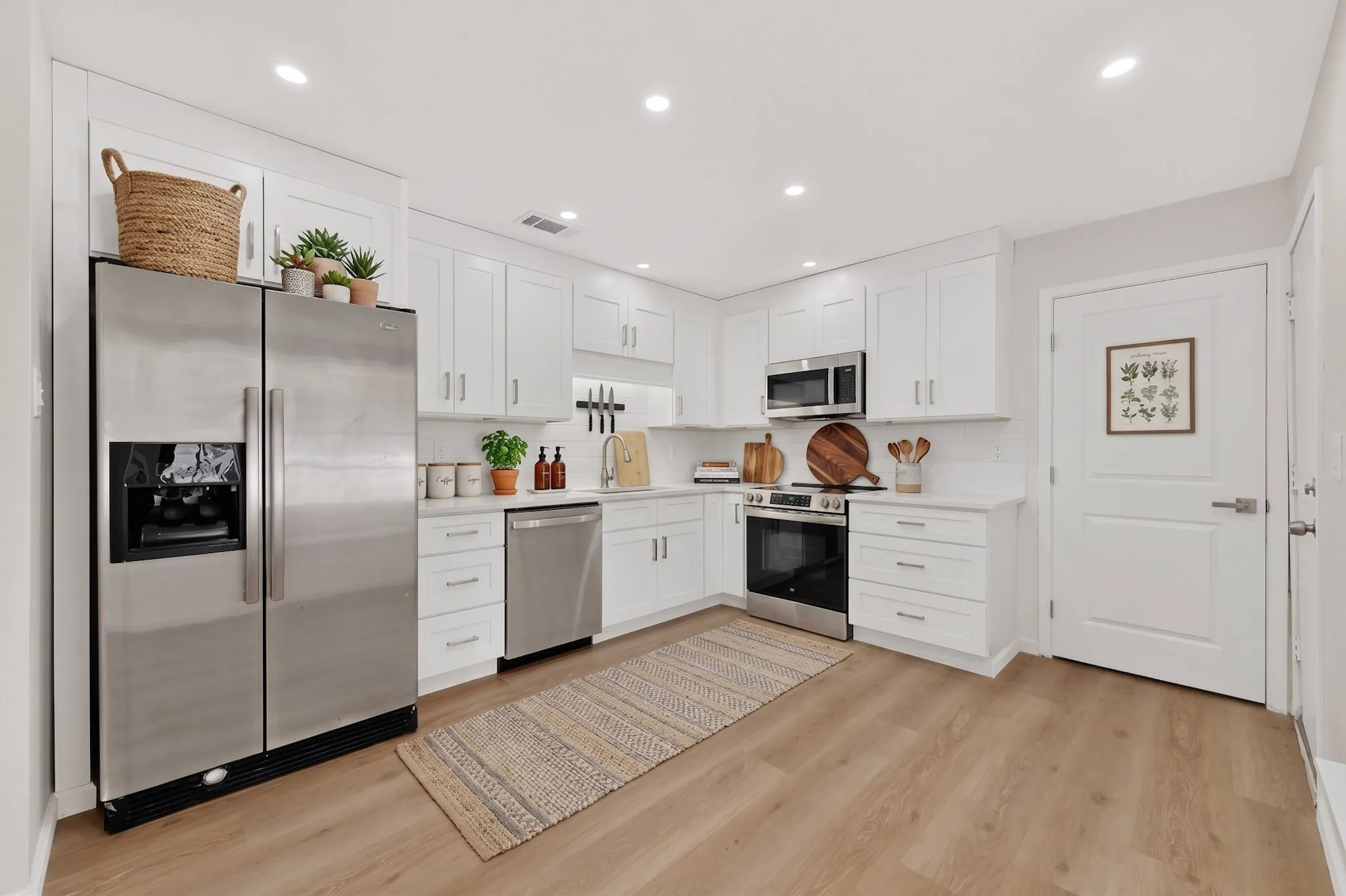 Kitchen featuring white cabinetry, wood-finish flooring, stainless steel appliances, recessed lighting, and a white subway tile backsplash