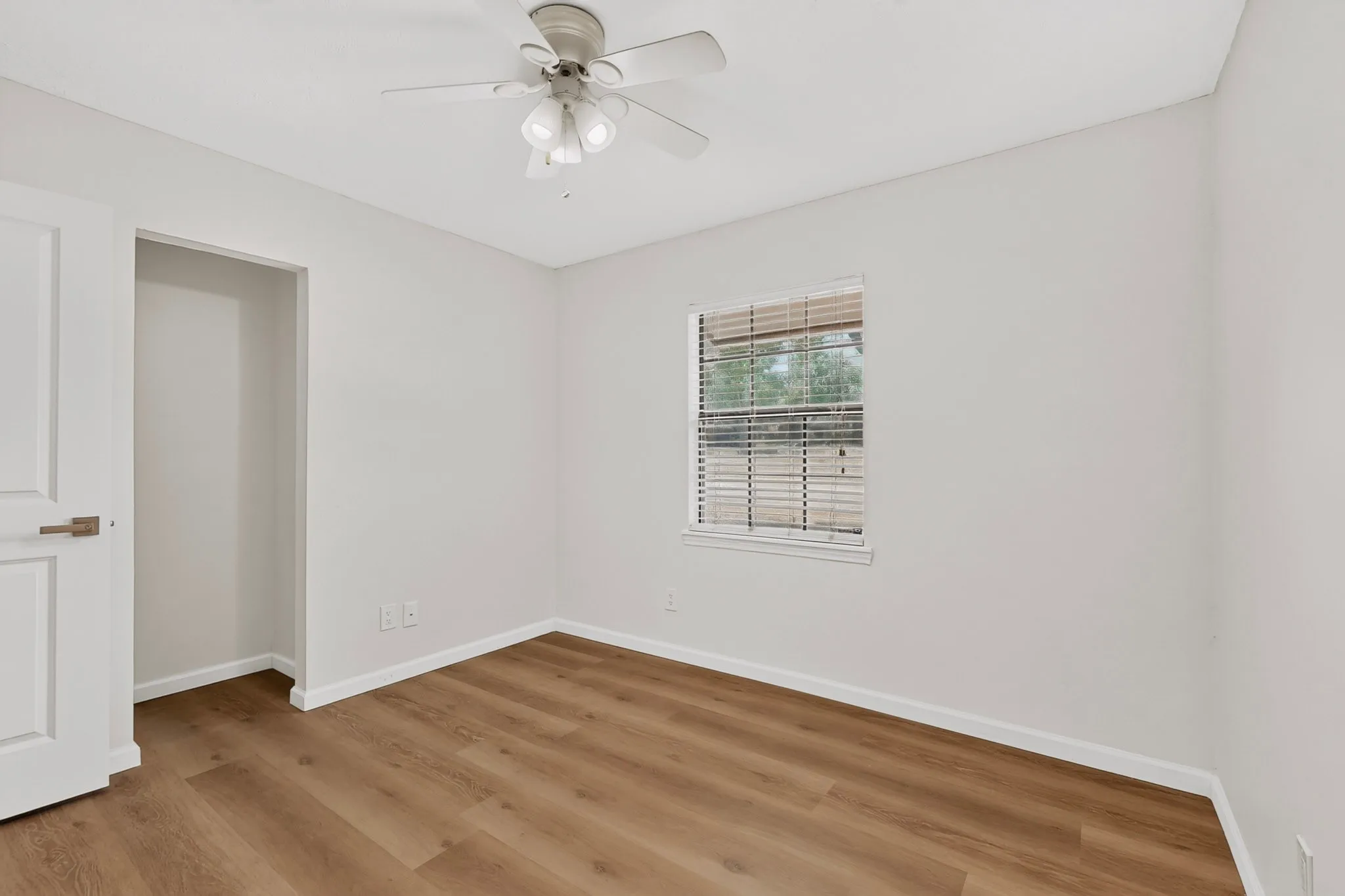 Room featuring wood-finish flooring, a window with blinds, and a ceiling fan