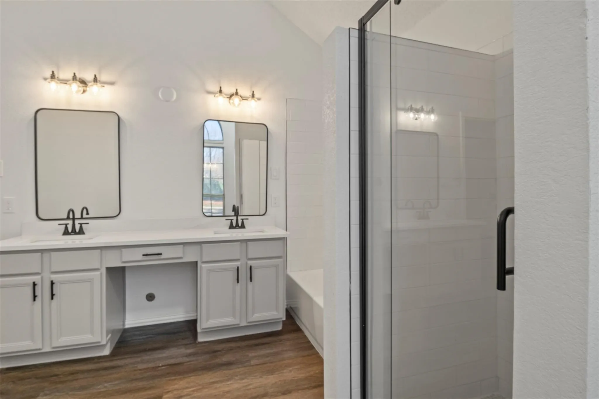 Dual vanities with white cabinetry, integrated sinks, and matte black fixtures