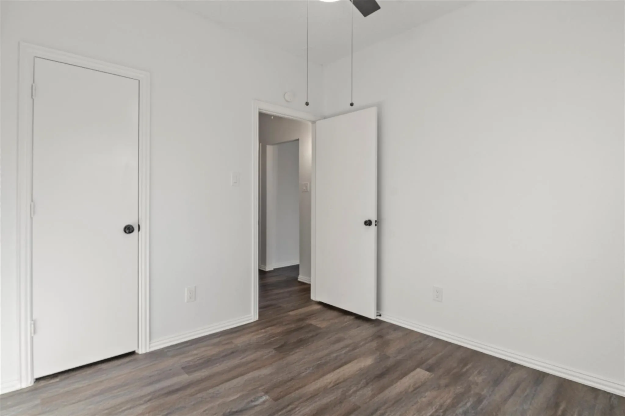 Wood-finish flooring, white painted walls, and a ceiling fan