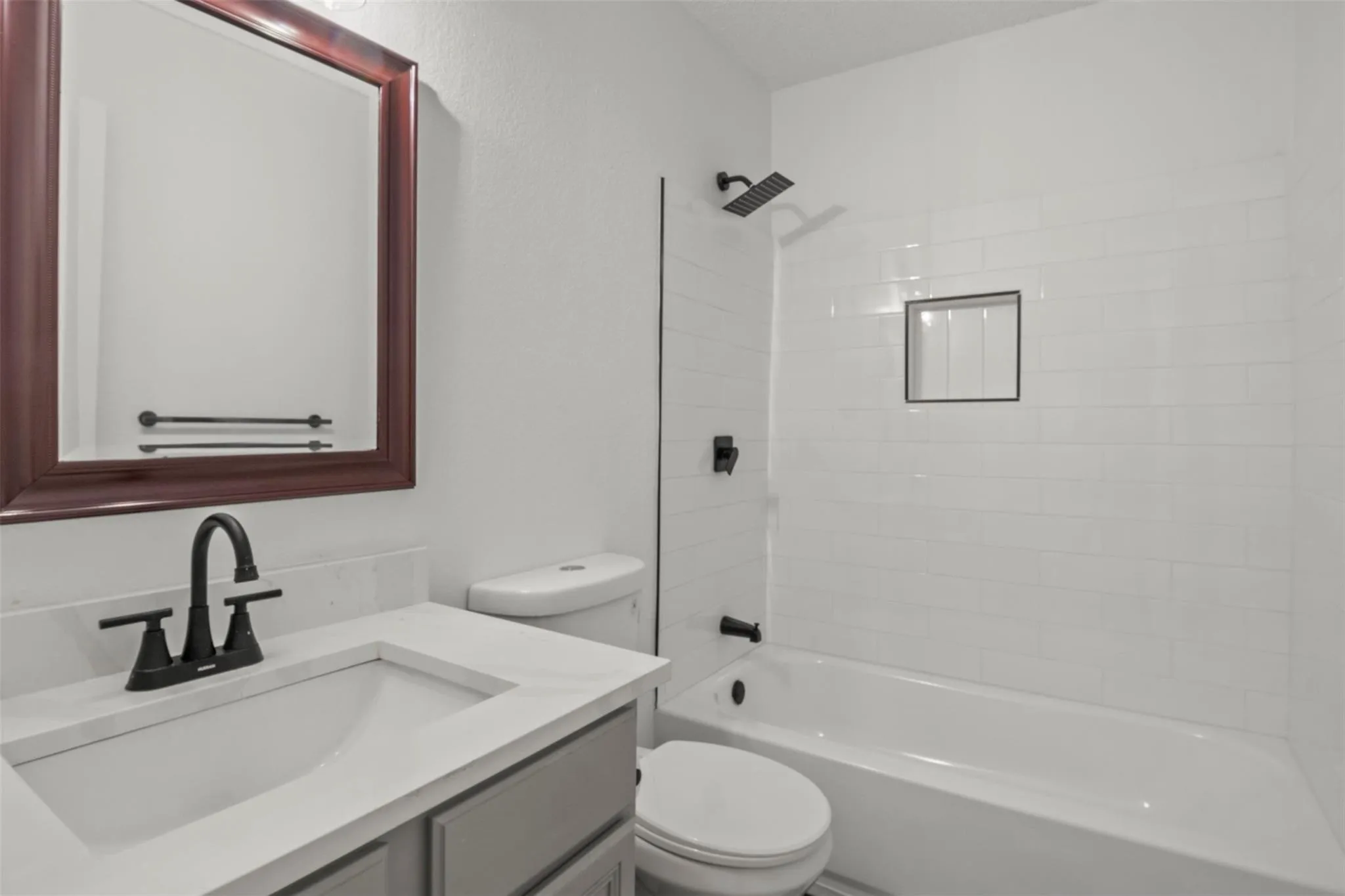 Vanity with an integrated sink, black-finish faucet, and a framed mirror