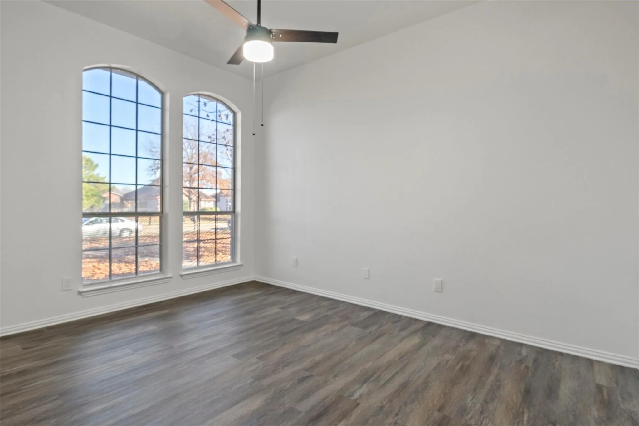 Arched windows, ceiling fan, and wood-finish flooring