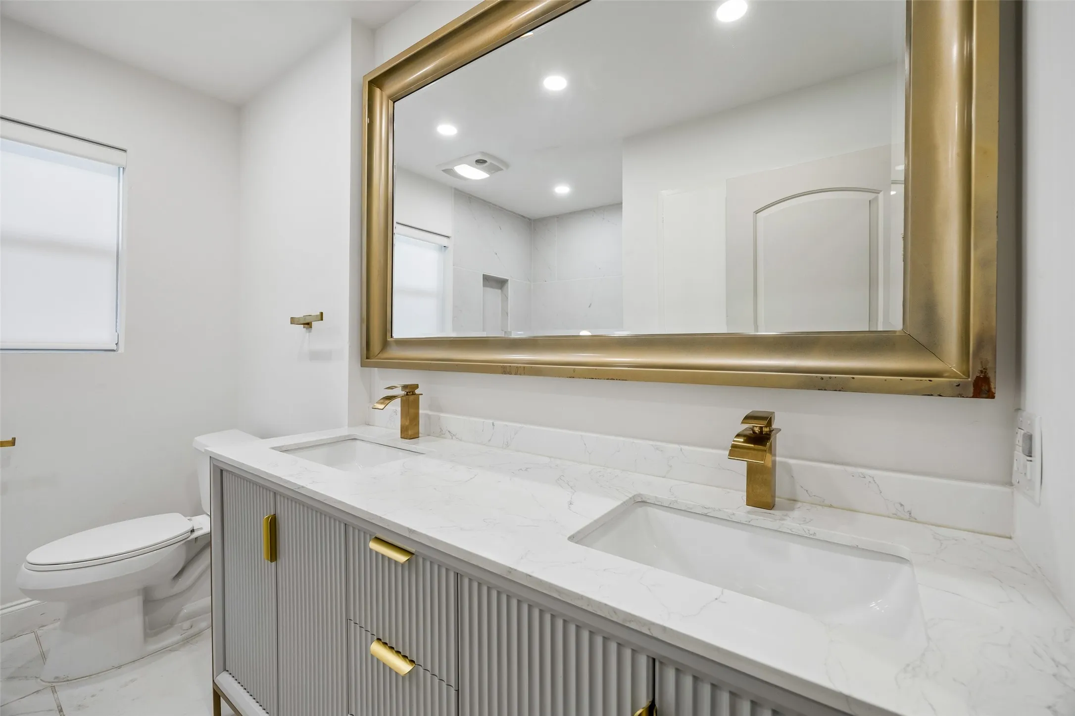 Dual vanity with integrated rectangular sinks, a light-toned countertop, and gold-finish faucets