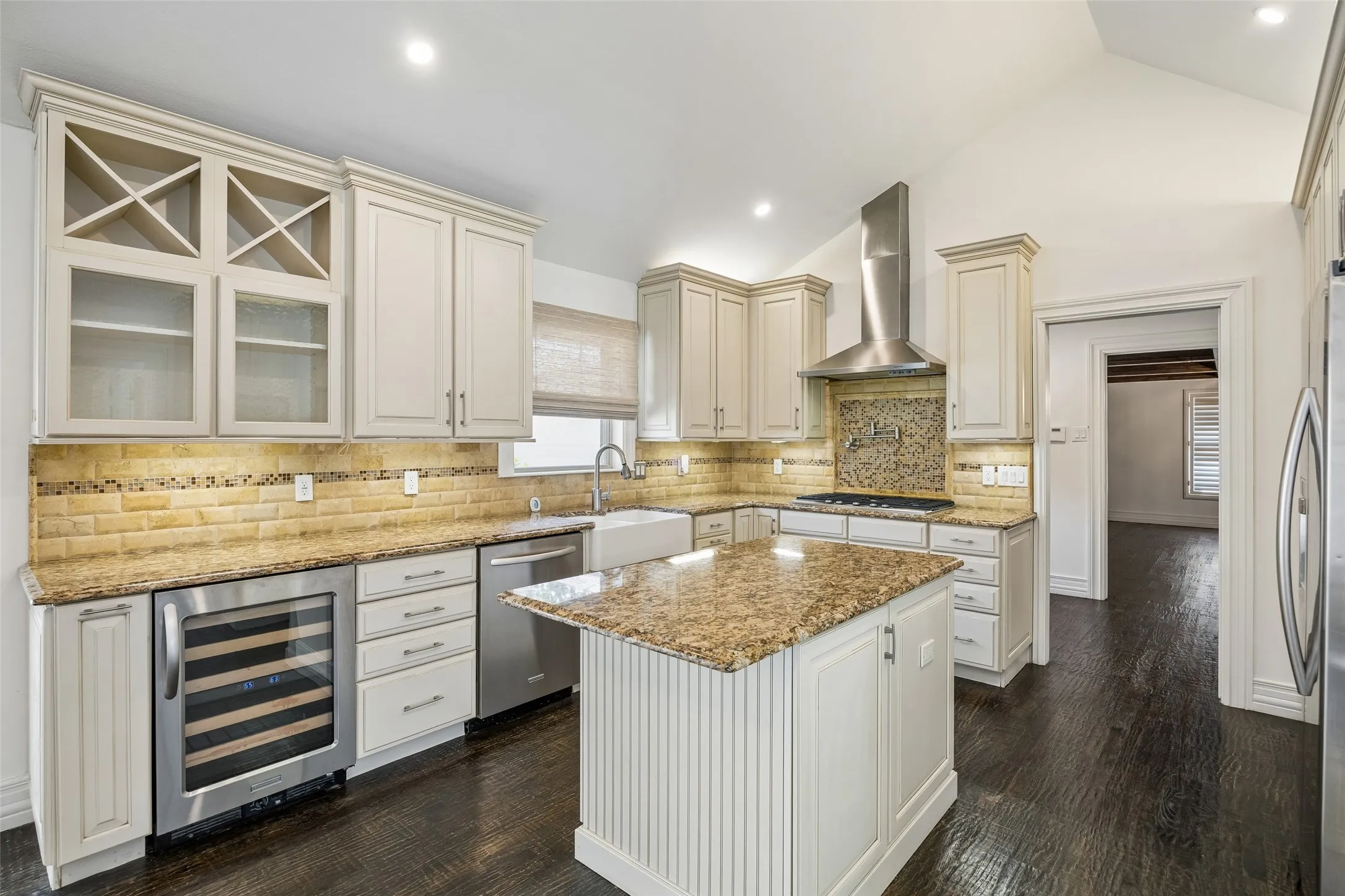 Kitchen with light-toned cabinetry, granite countertops, and a tile backsplash