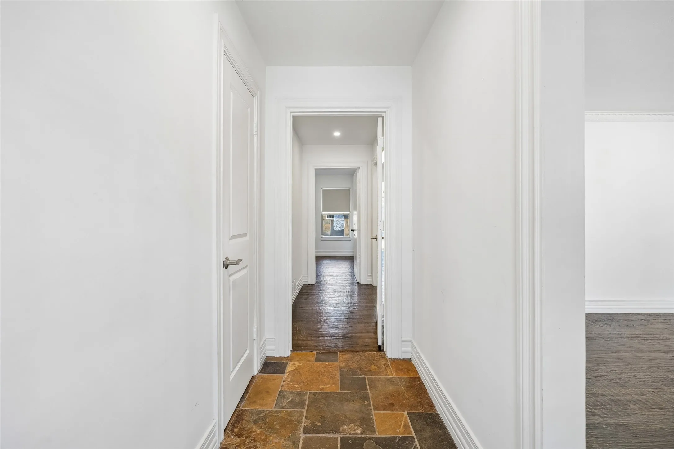 Hallway featuring multi-toned slate flooring and white trim