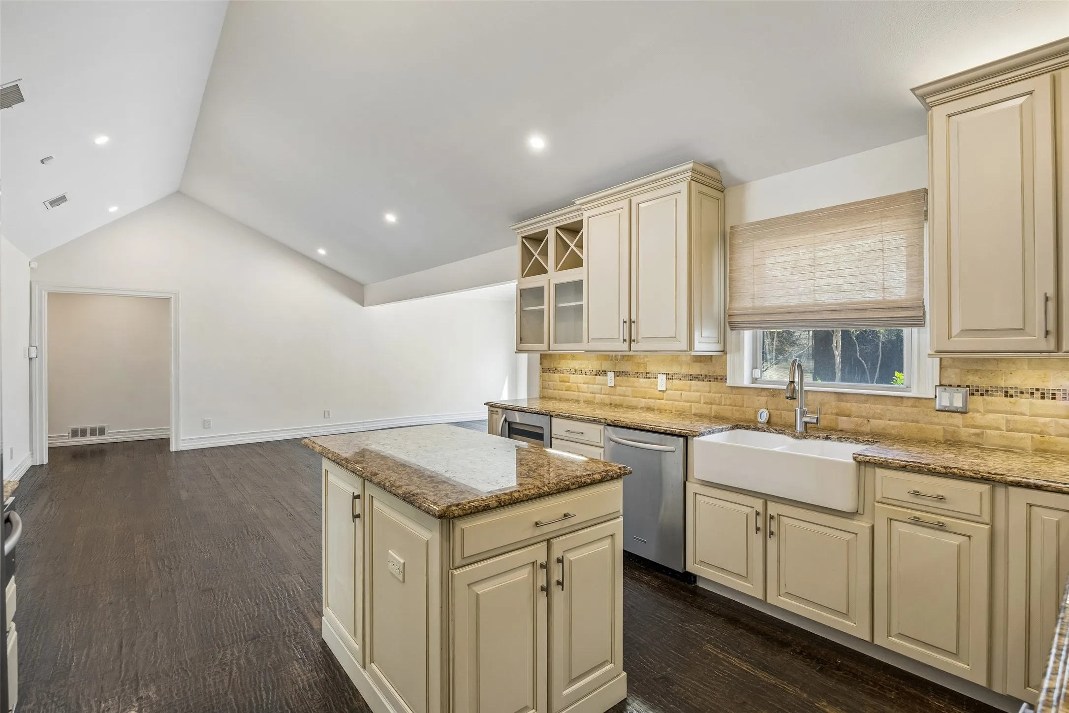 Kitchen island with integrated cabinetry, farmhouse sink, stainless steel dishwasher, and under-cabinet lighting
