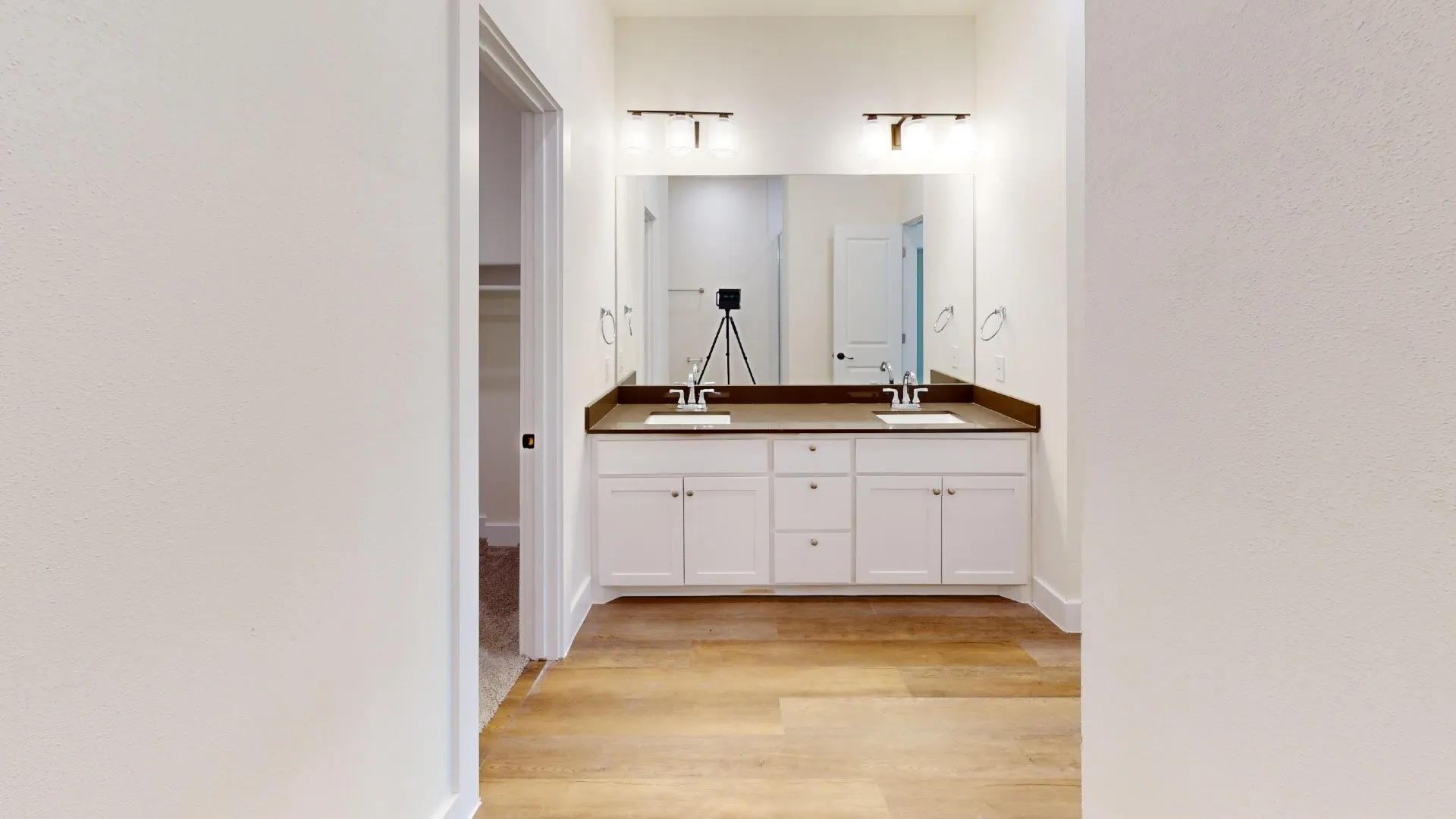 Dual vanity with integrated sinks, dark countertop, and wood-finish flooring