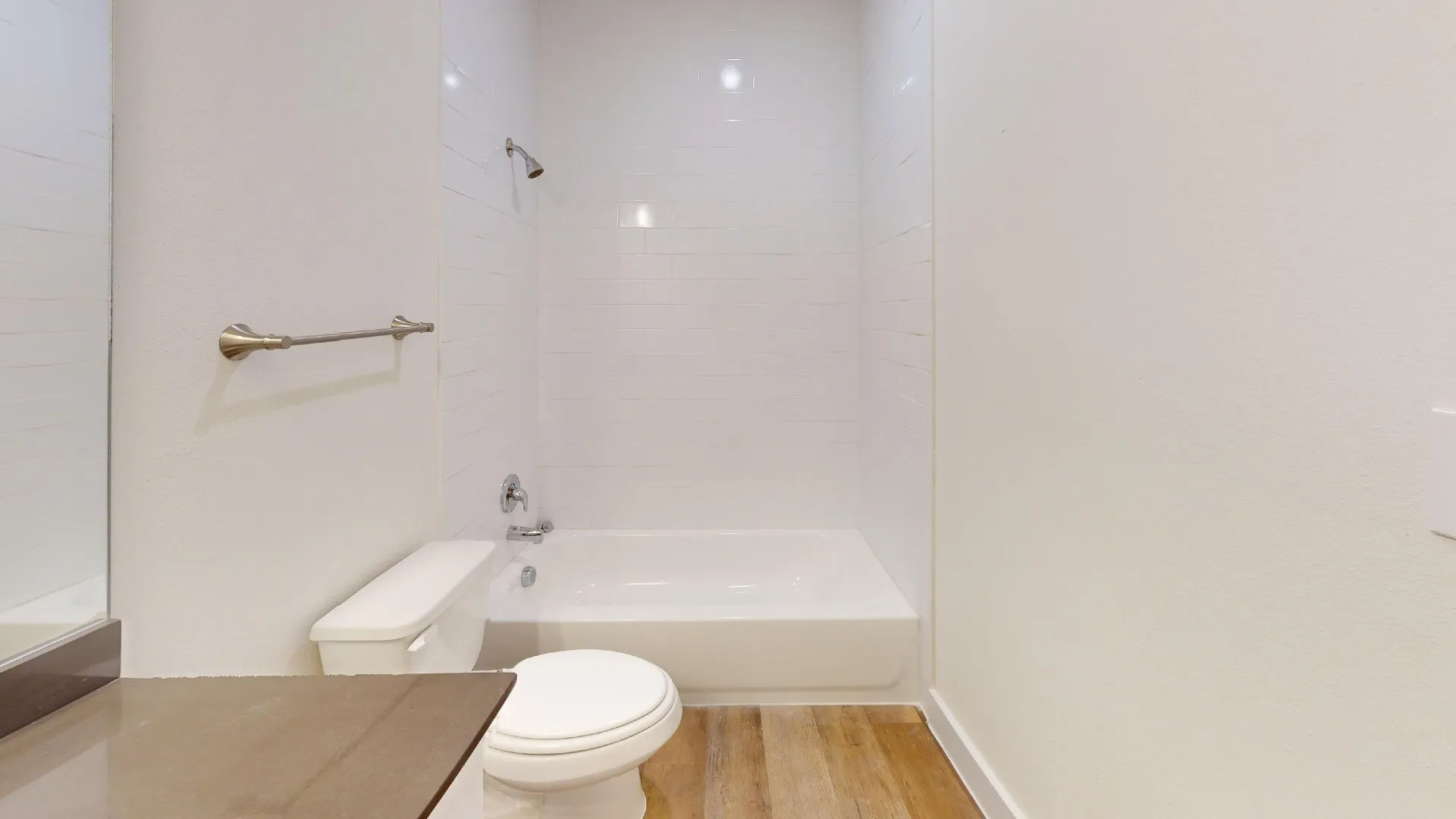 Bathroom featuring a shower/tub combination, wall-mounted showerhead, and wood-finish flooring