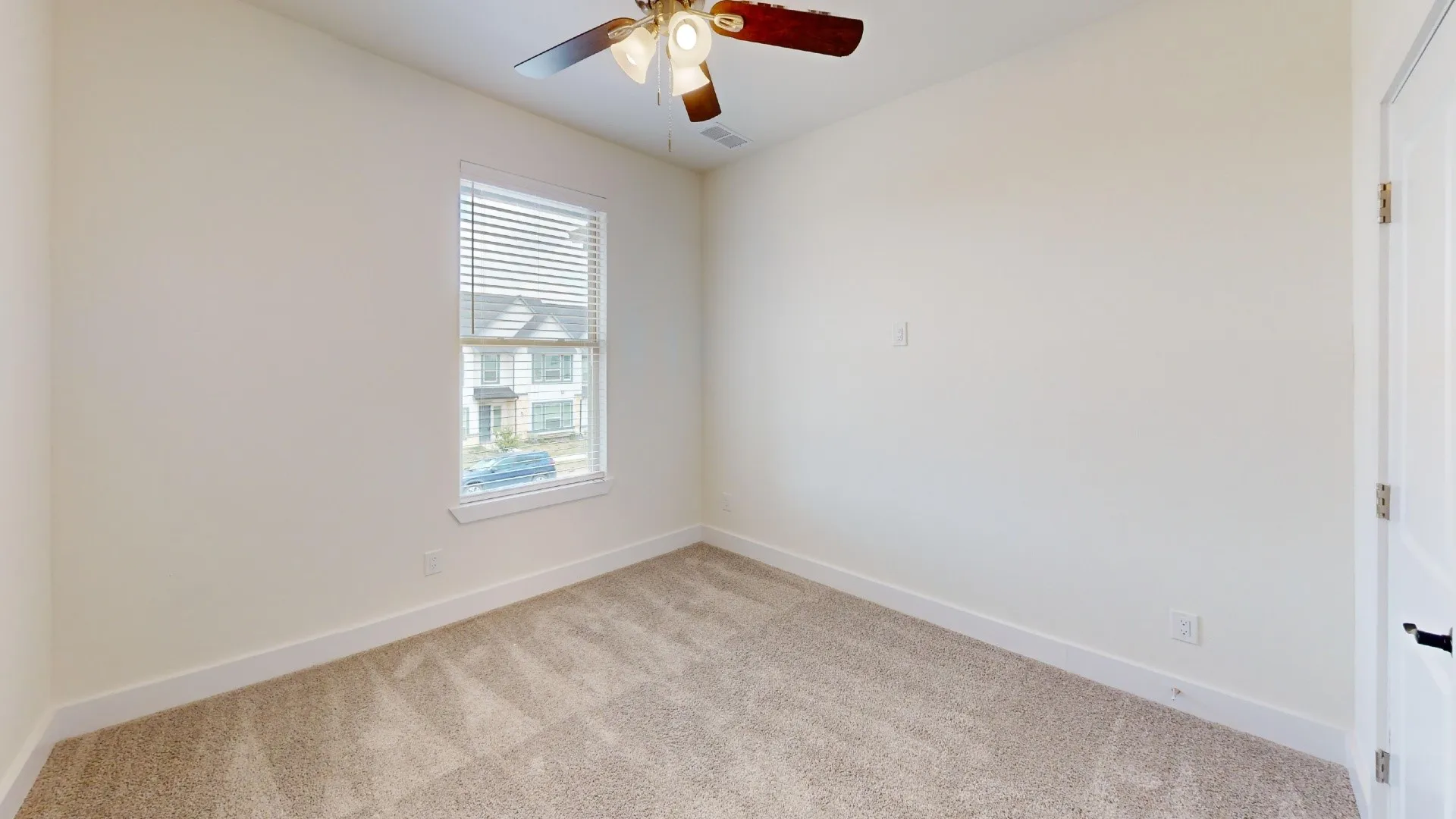 Neutral wall tones, carpeted flooring, a window with blinds, a ceiling fan, and a white paneled door