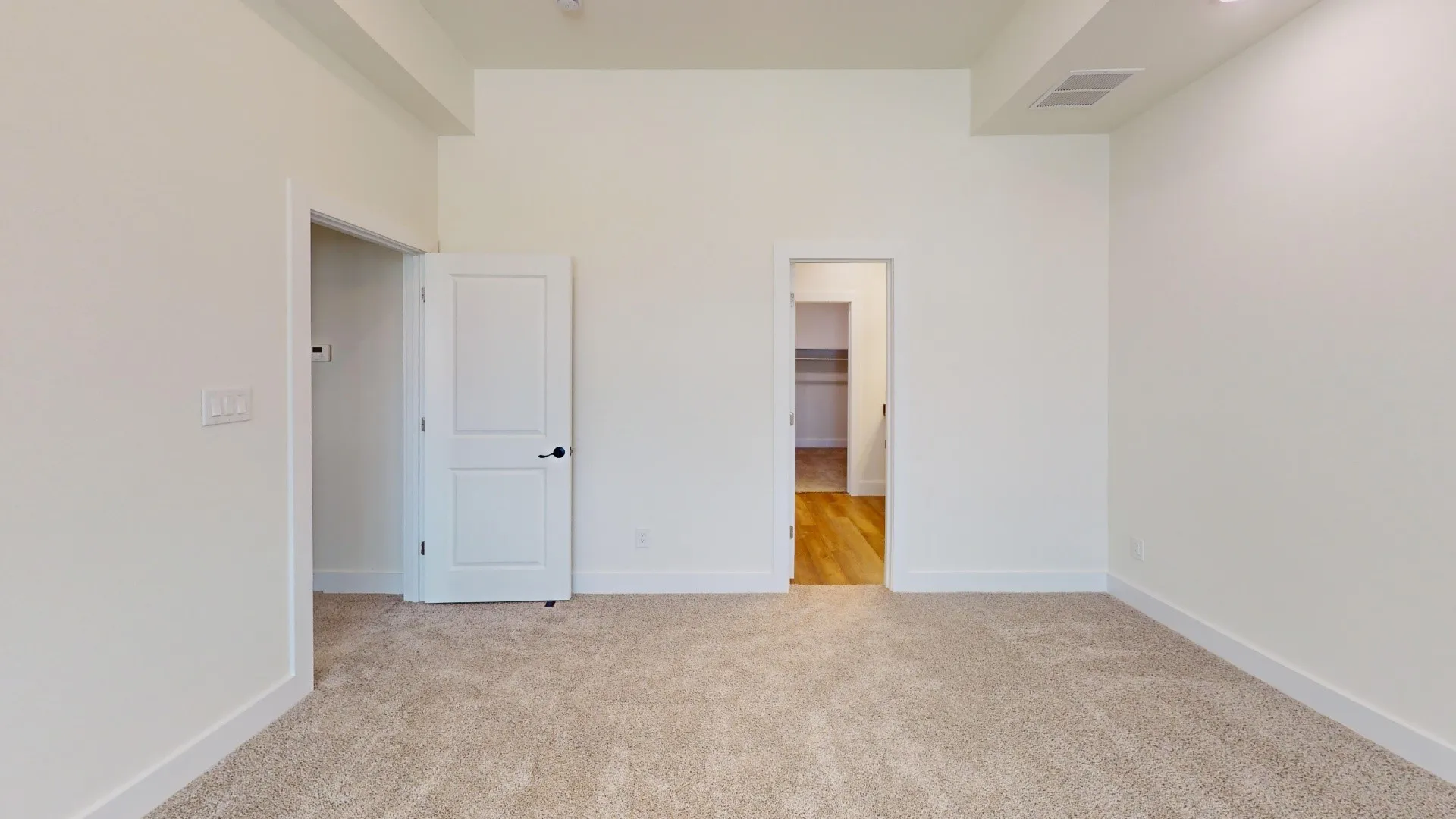 Bright interior space featuring neutral carpeting, white walls, and a recessed ceiling element