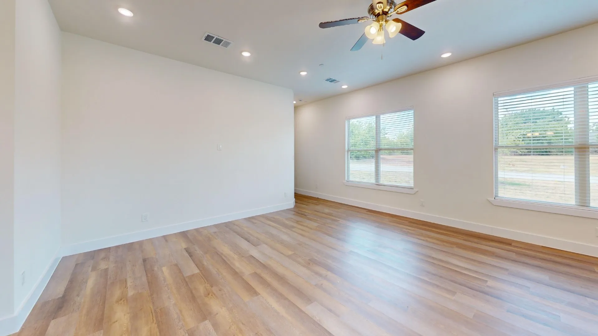 Recessed lighting, wood-finish flooring, and two windows with blinds