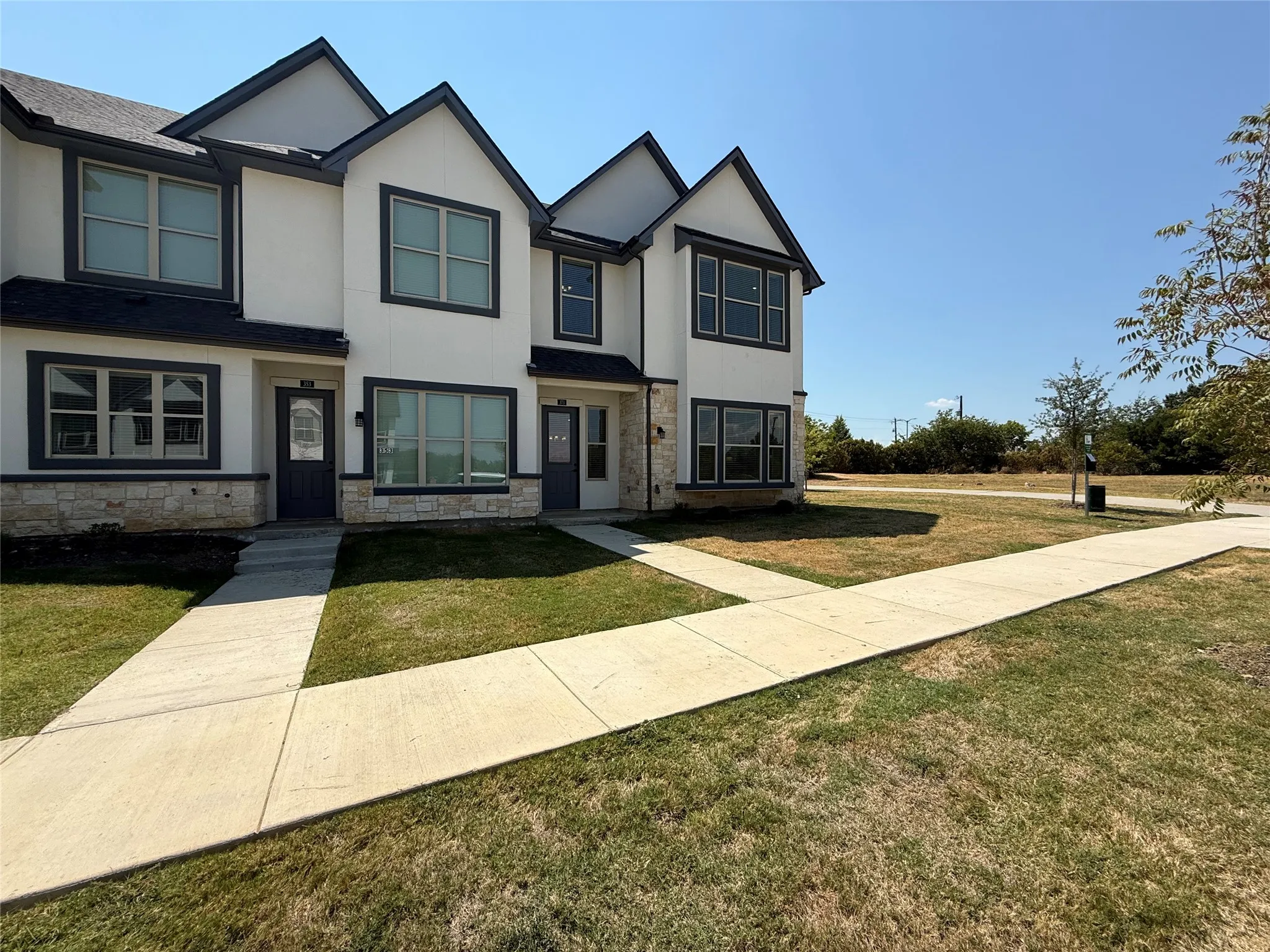 Contemporary architectural design with white siding and dark trim, stone veneer accents, and multiple windows