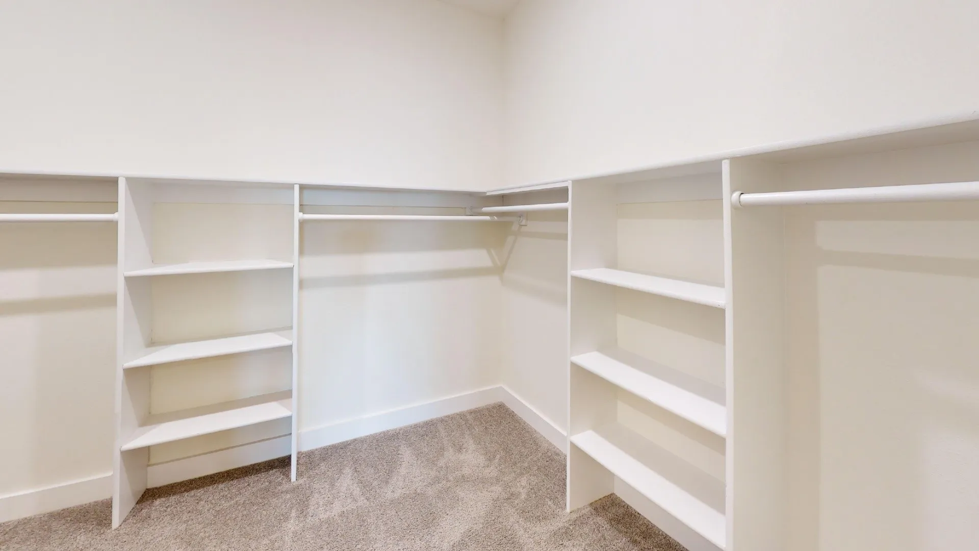 Built-in closet organization system featuring white shelving and hanging rods