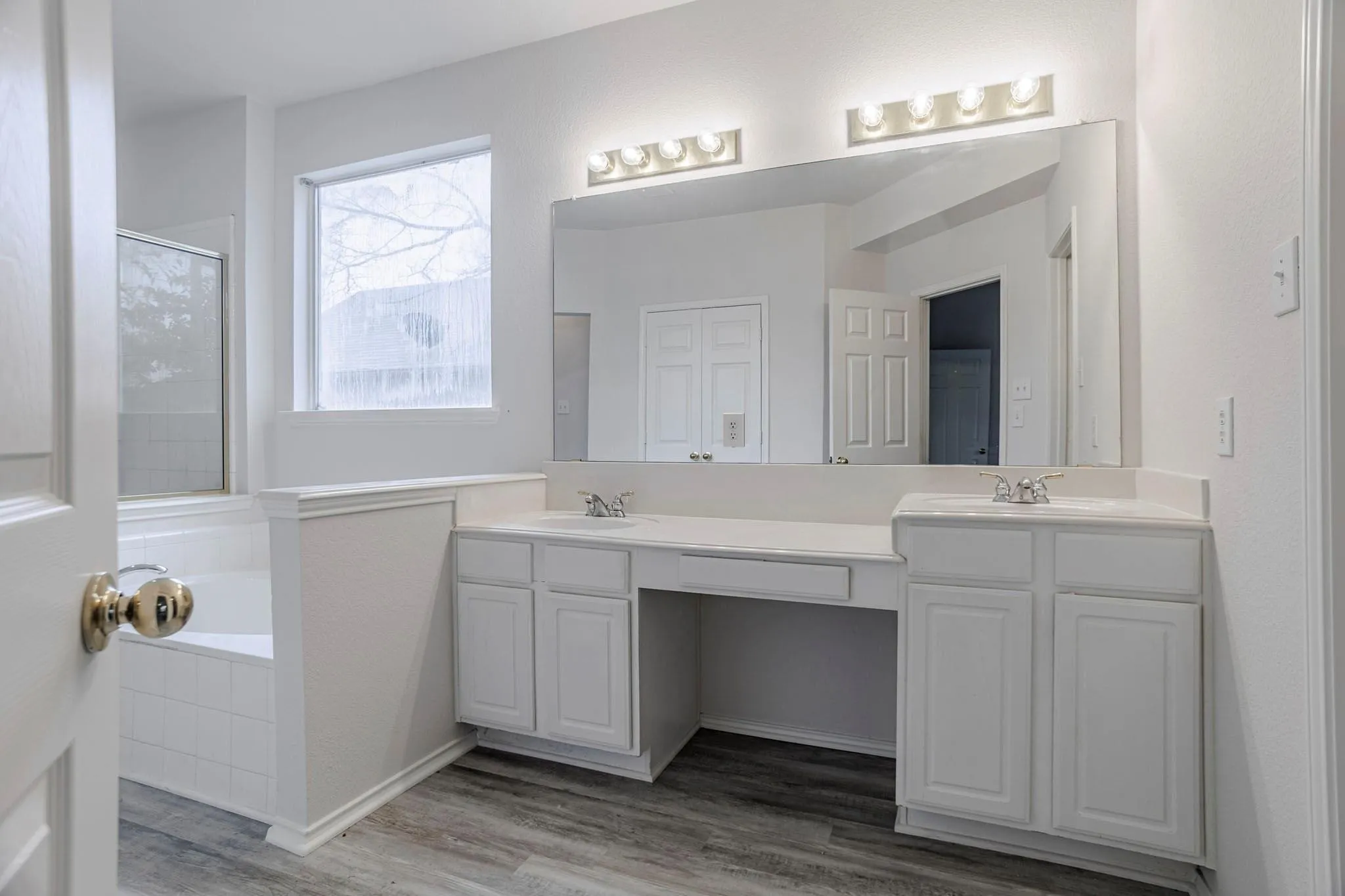 Dual vanity with white cabinetry, integrated sinks, white countertops, and a large mirror