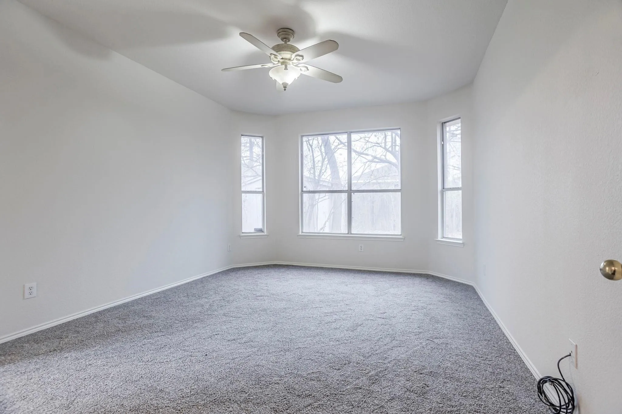Recessed ceiling with a ceiling fan, bay window configuration, gray carpeting, and neutral wall tones