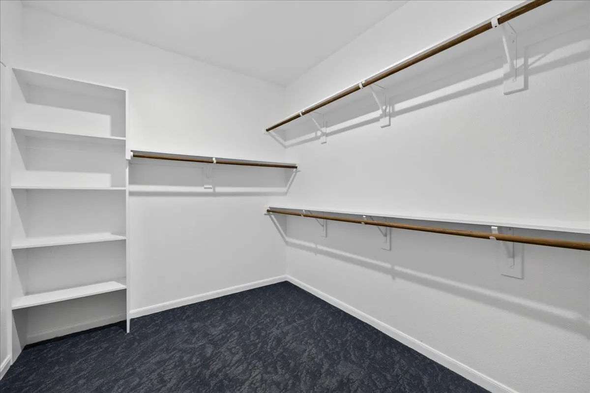 Built-in shelving, multiple hanging rods, durable carpet flooring, and white painted walls