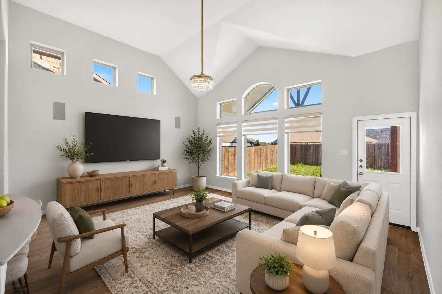 Vaulted ceiling, wood-finish flooring, multiple windows, built-in wall speakers, and a ceiling-mounted light fixture