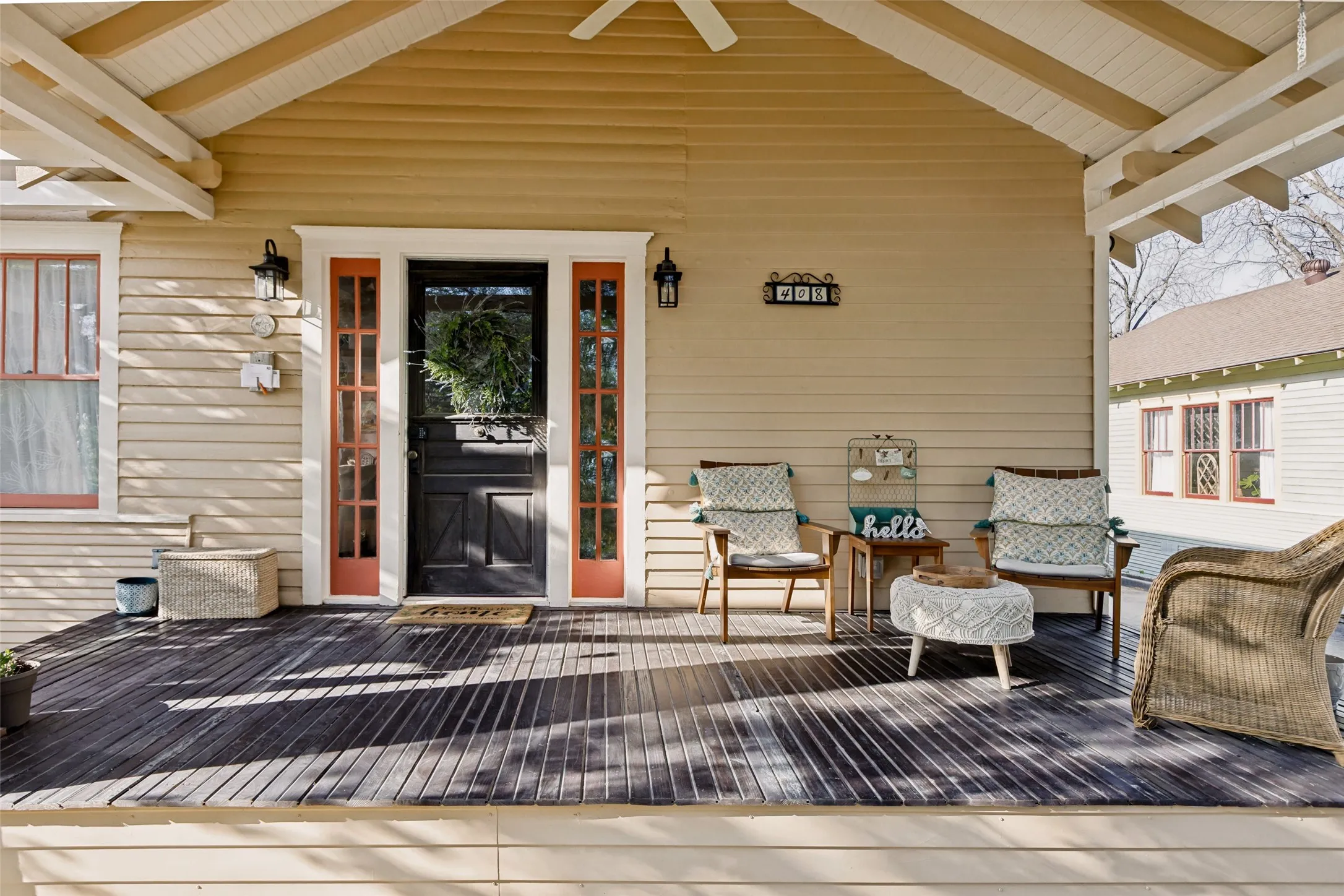 Expansive covered porch with dark wood-finish decking, light wood siding, and white trim