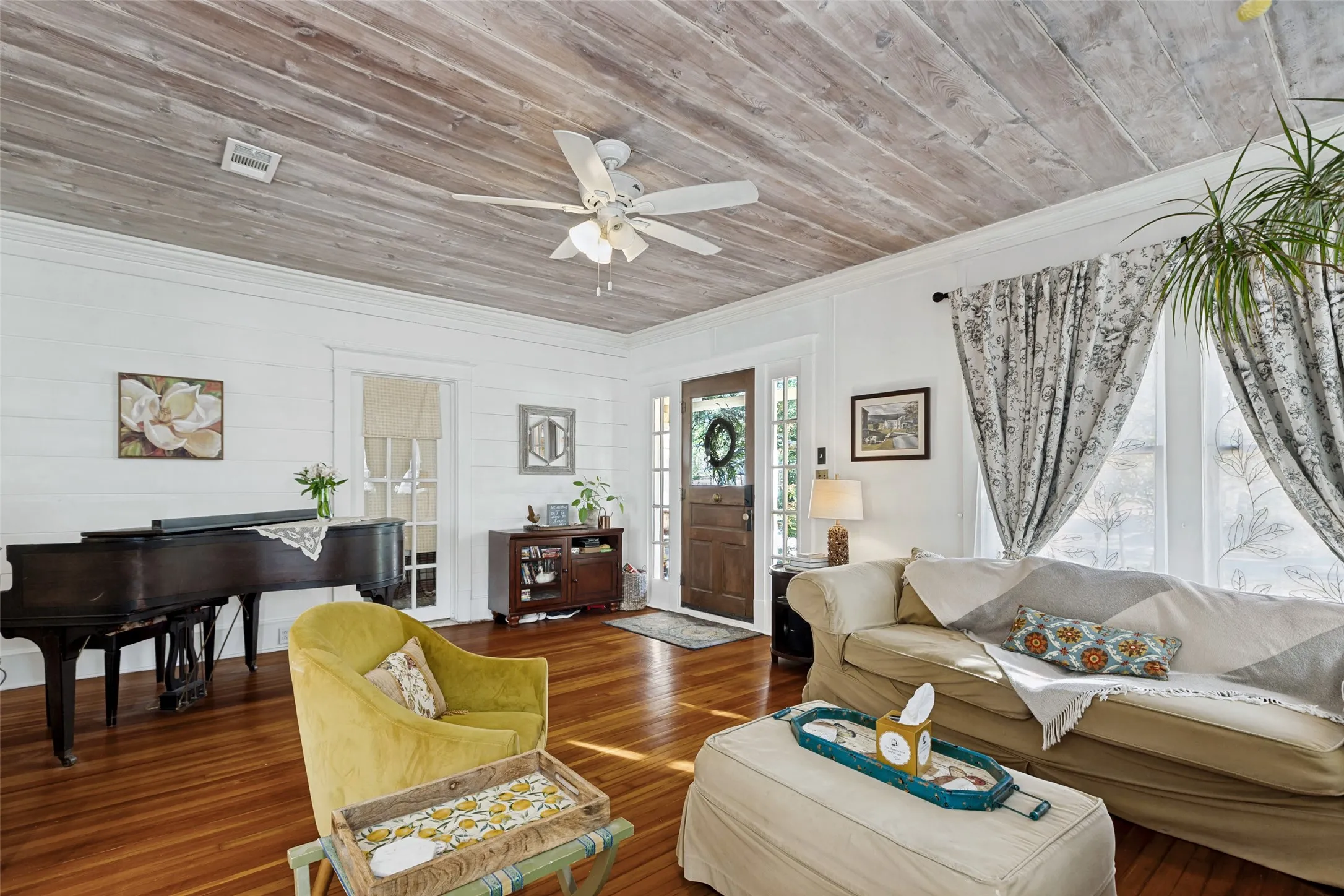 Wood-finish plank ceiling with a ceiling fan, wide plank wood-finish flooring, white shiplap walls, and a wood-panel entry door