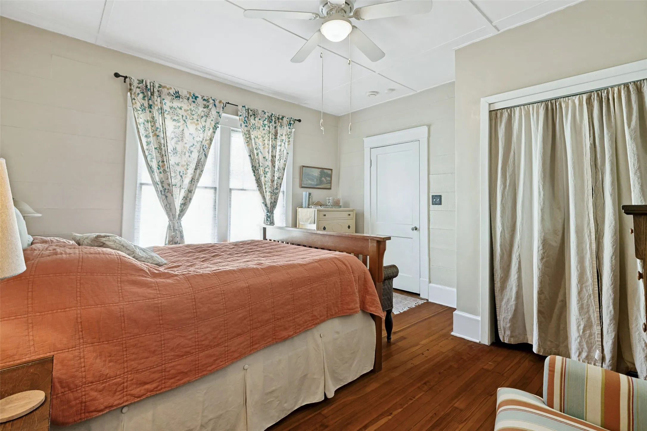 Hardwood flooring, painted paneled walls, ceiling fan with integrated lighting, white trim, and a white interior door