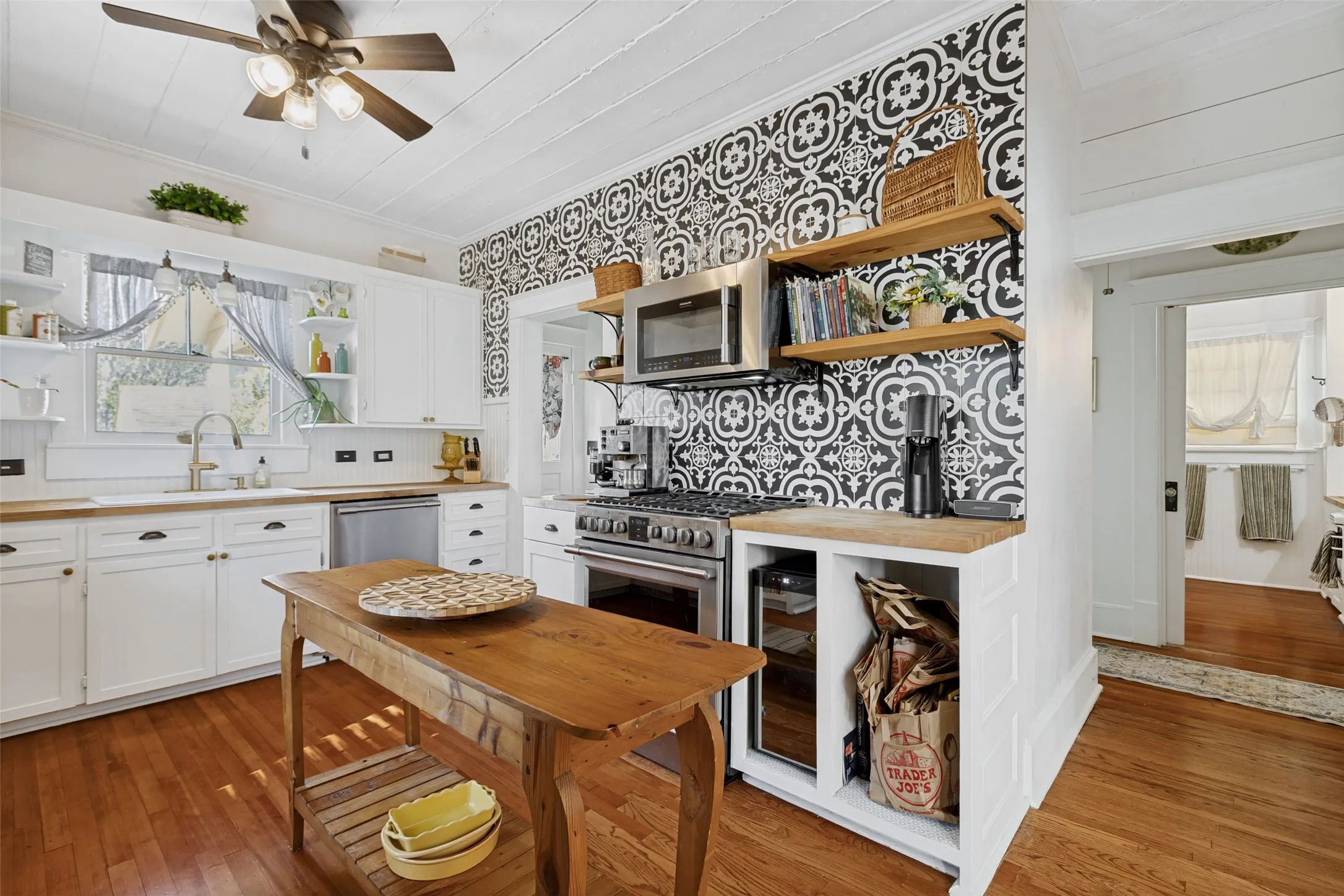 Kitchen featuring wood-finish flooring, white cabinetry, wood countertops, a stainless steel gas range, and a patterned tile backsplash