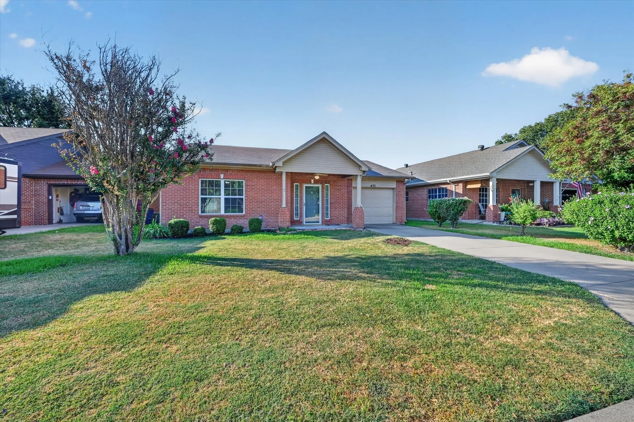 Brick exterior with a gabled entry, attached garage, and a concrete driveway