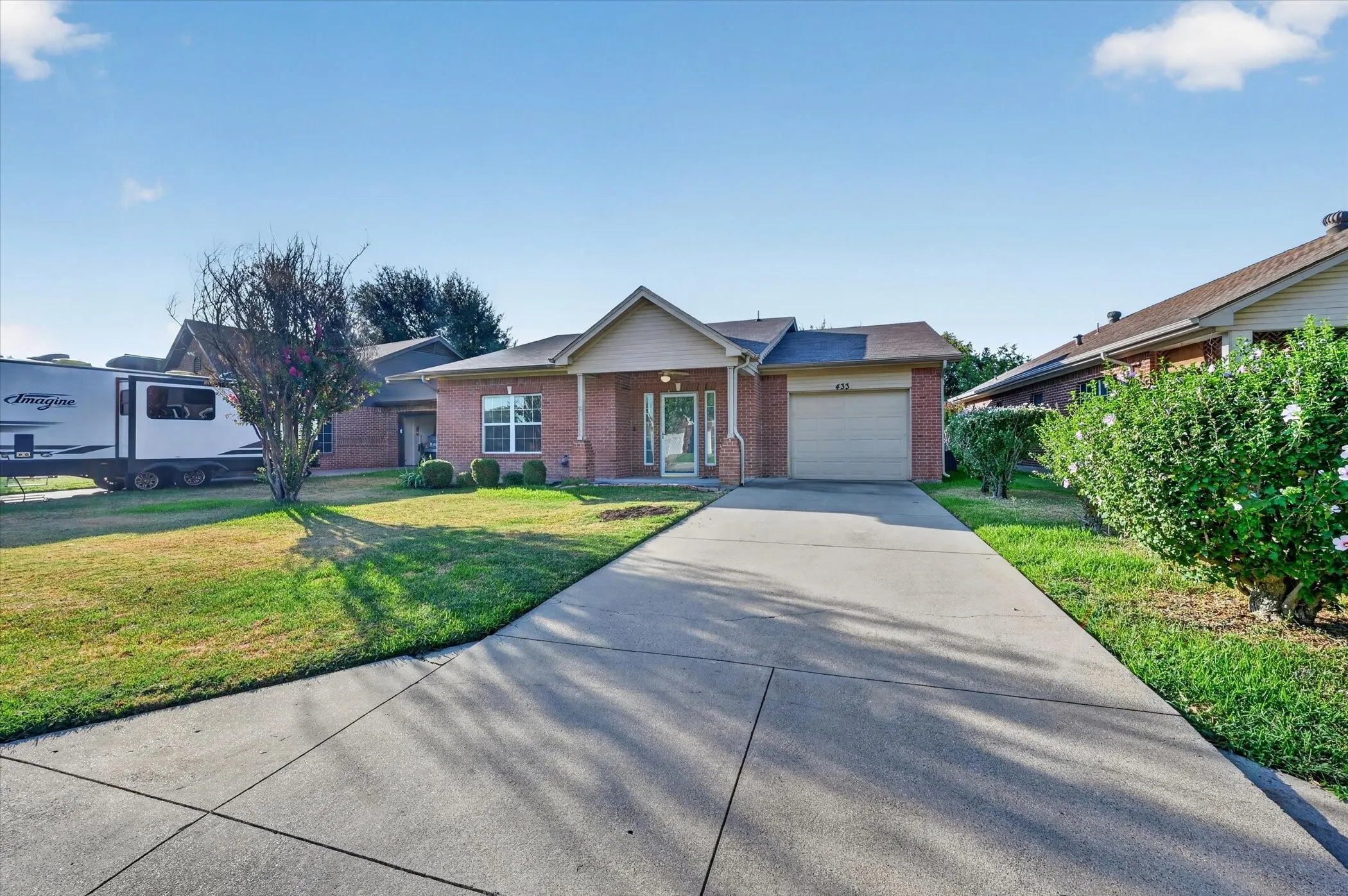 Red brick exterior with an attached single-car garage and a concrete driveway
