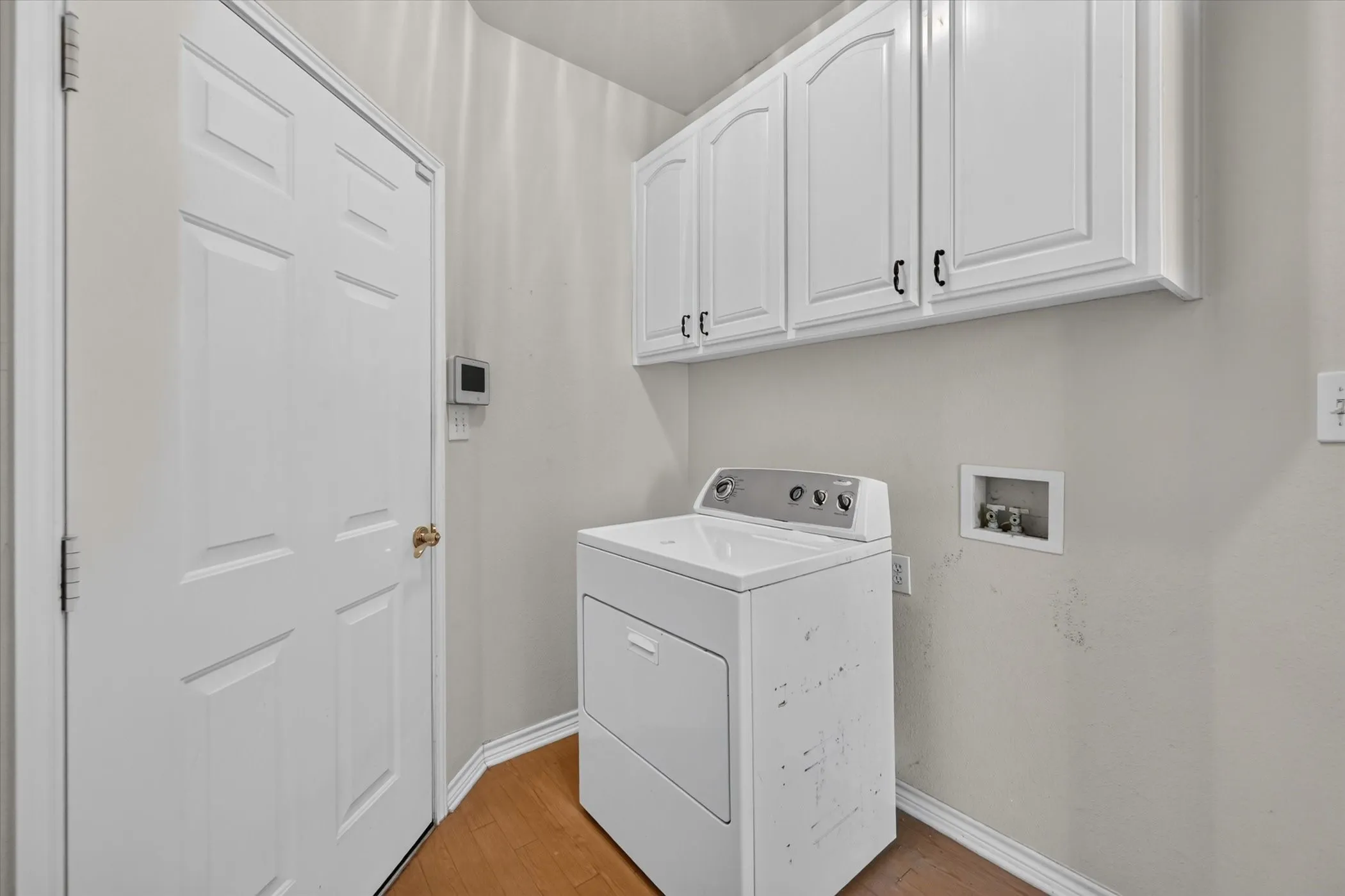 White shaker-style cabinetry with dark hardware, wood-finish flooring, and a white paneled door