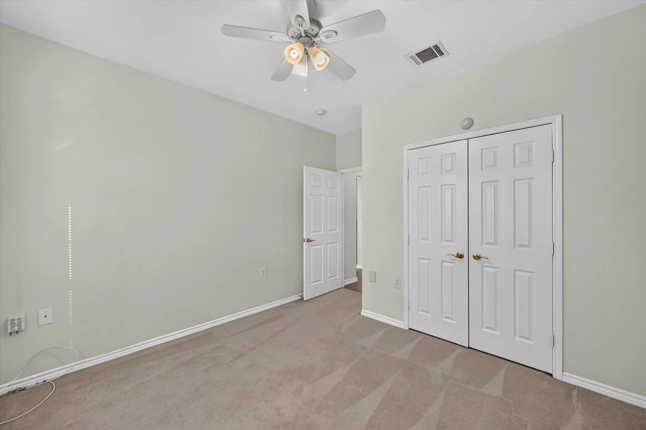 Neutral wall paint, carpet flooring, ceiling fan with integrated lighting, and white paneled doors