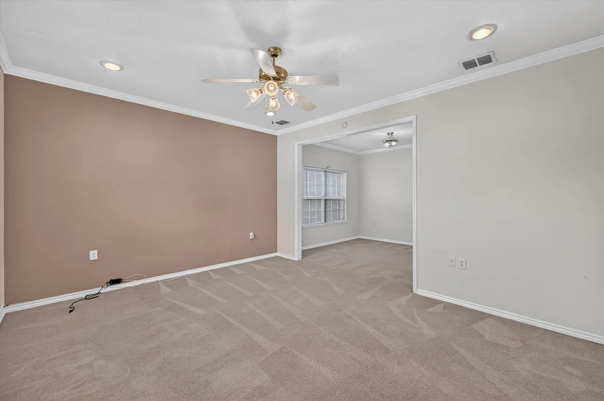 Recessed ceiling lighting, ceiling fan light fixture, crown molding, cased opening to additional space, and patterned carpeting