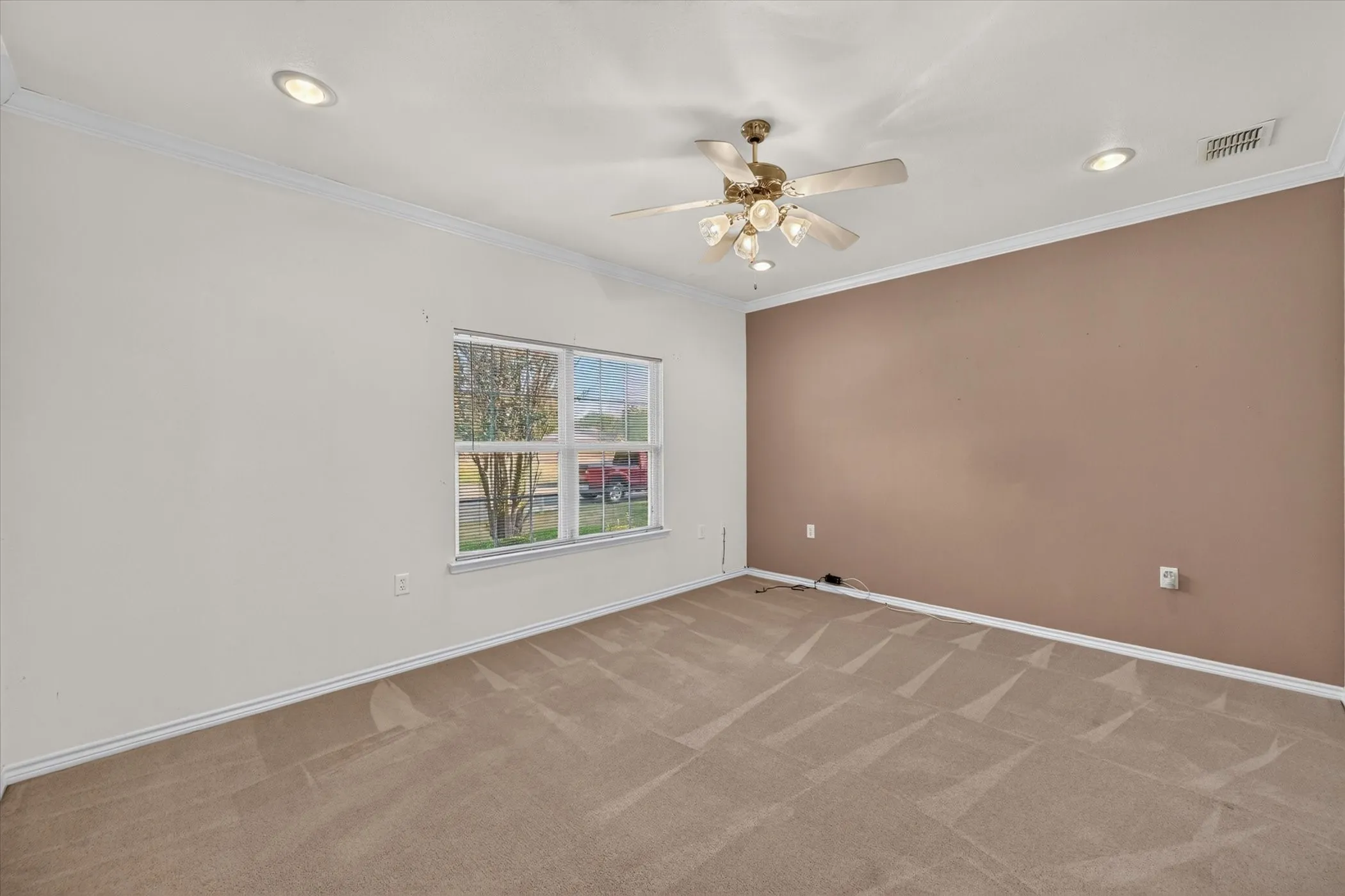 Recessed lighting, ceiling fan light fixture, crown molding, two-tone wall finish, and neutral carpeting