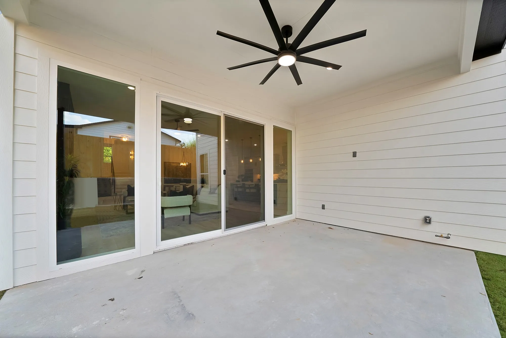 Covered patio with concrete flooring, shiplap siding, and a modern ceiling fan with integrated lighting
