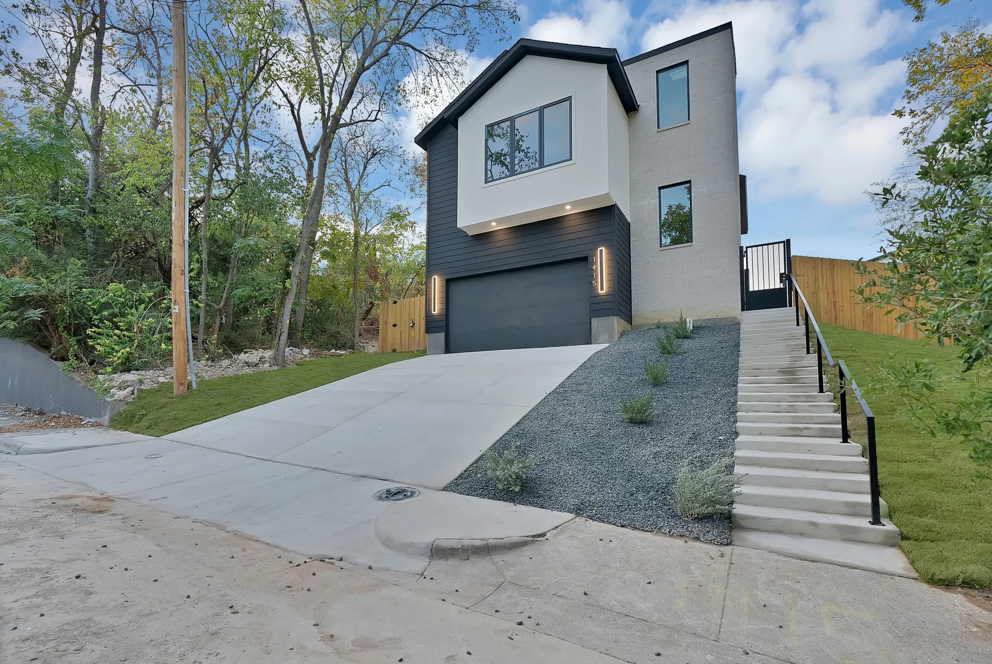 Modern exterior featuring dark gray siding, light gray brick, and white stucco accents
