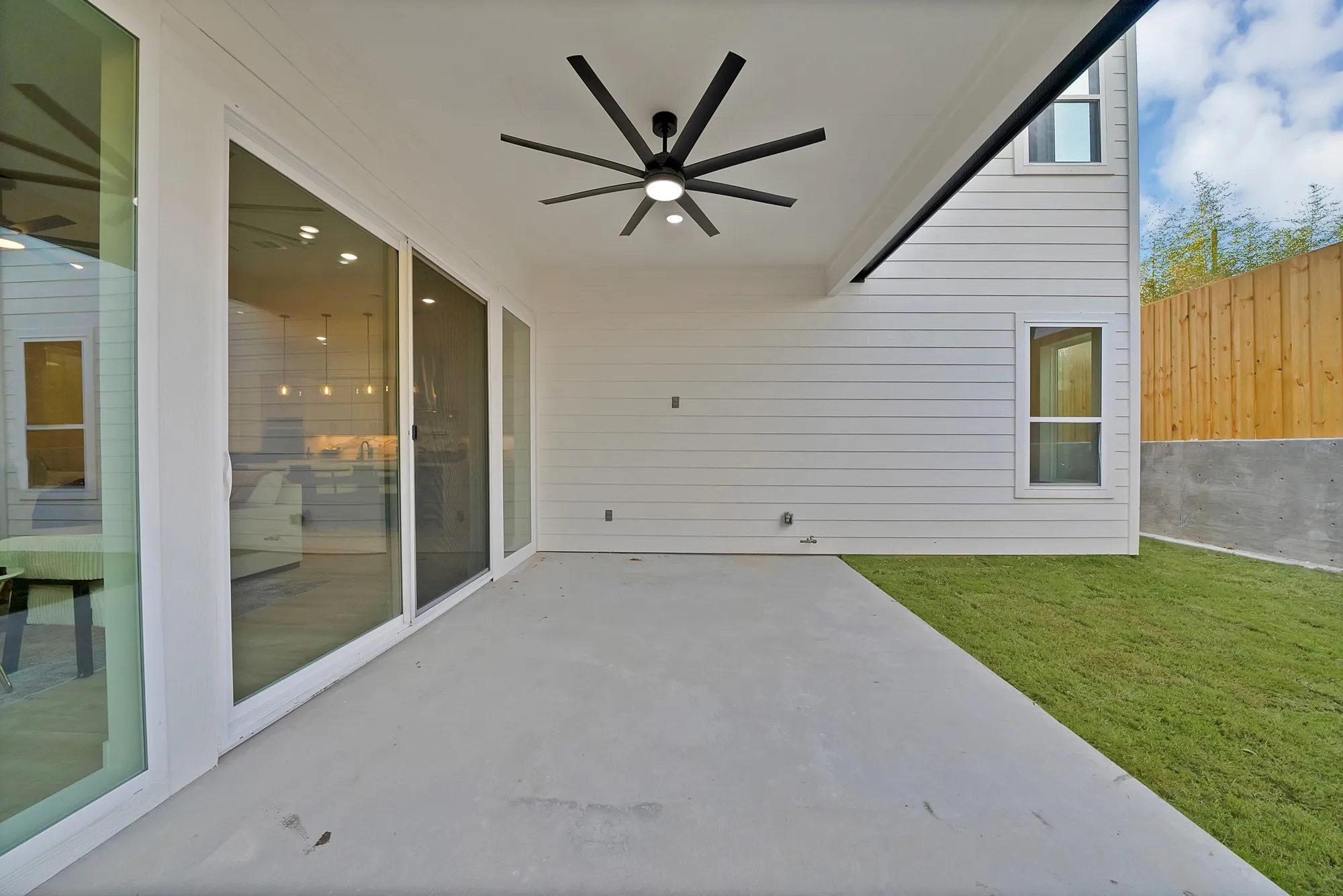 Covered patio featuring a ceiling fan, concrete flooring, and sliding glass doors