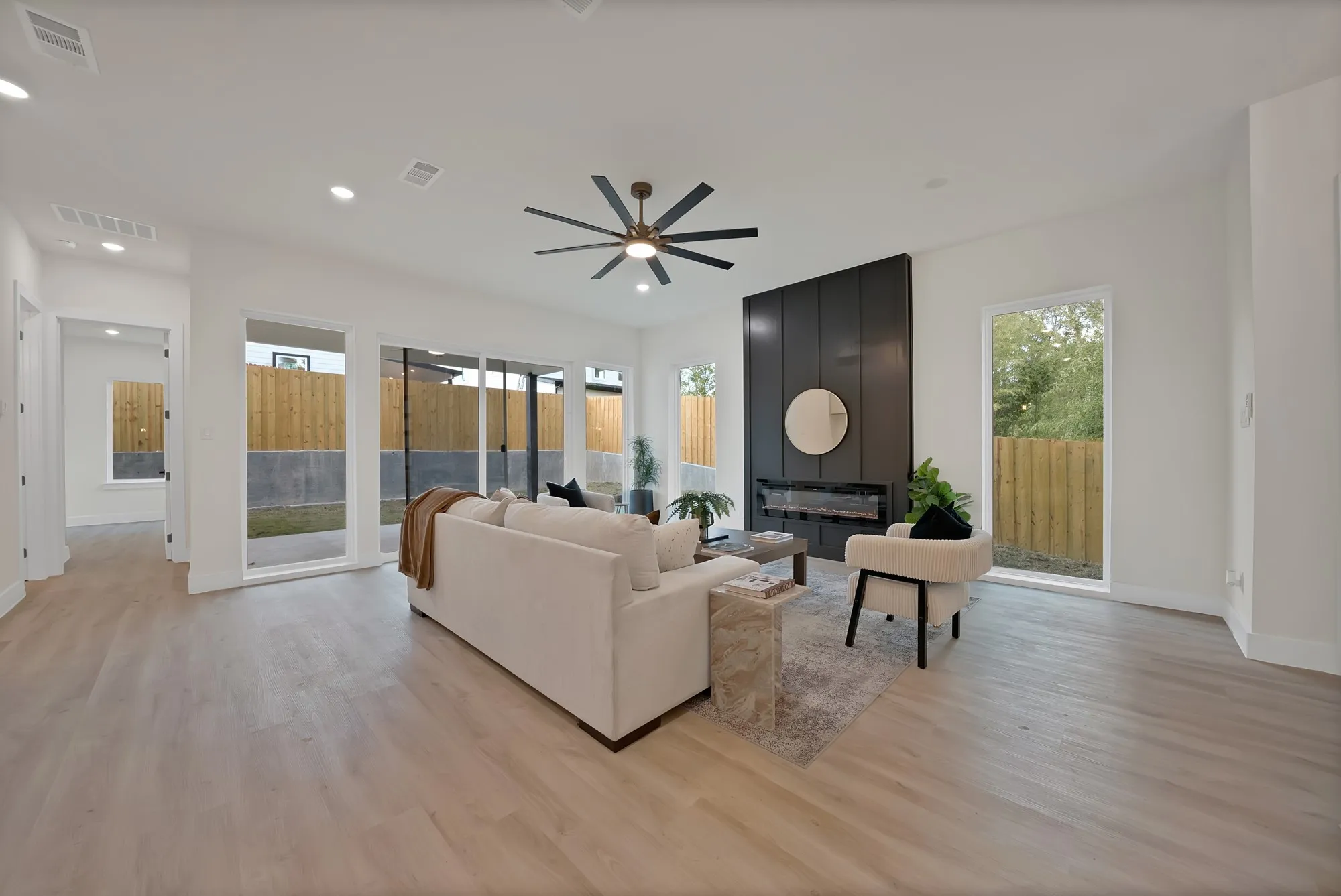 Wood-finish flooring, recessed lighting, and a dark accent wall with an integrated linear fireplace