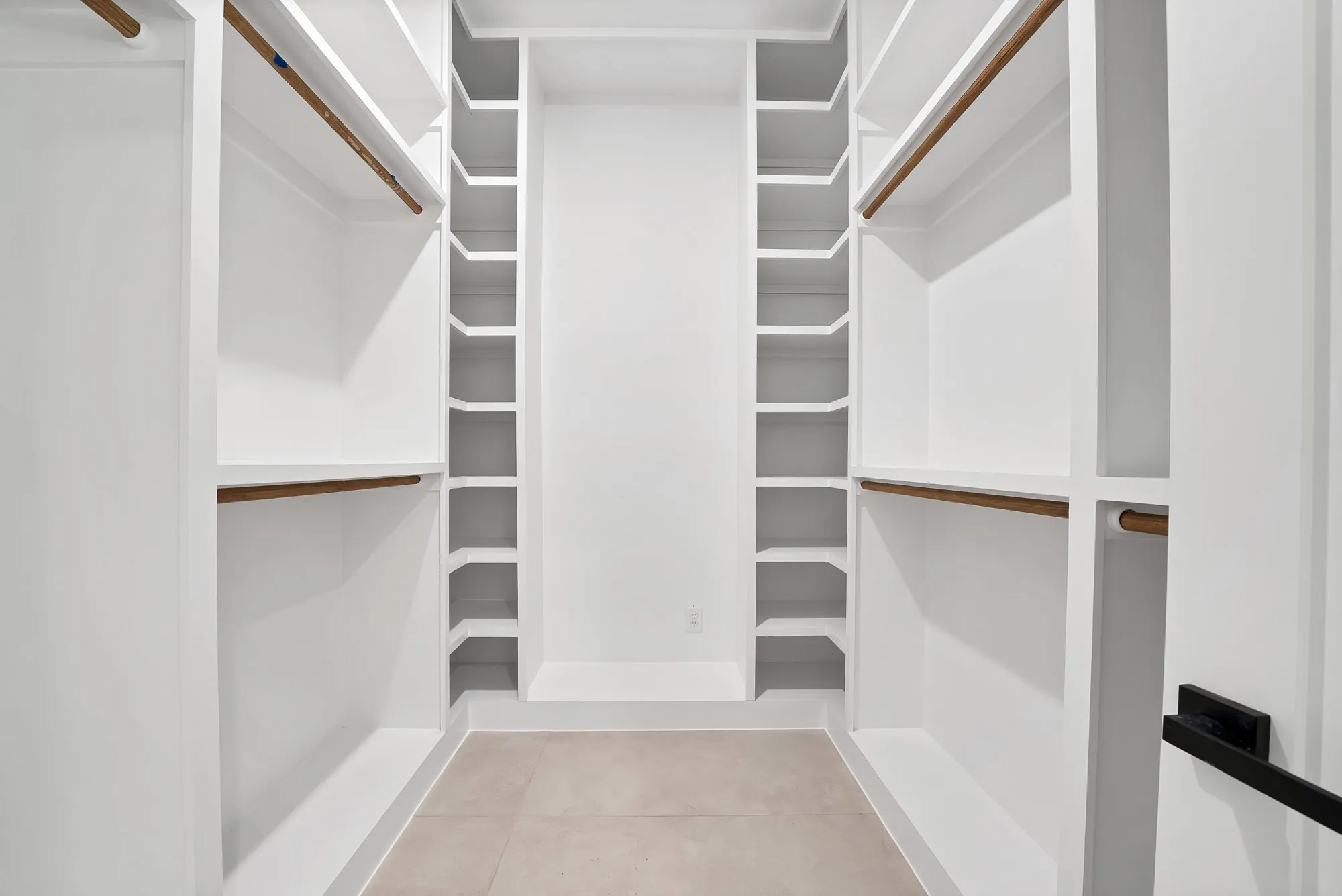 Built-in custom closet system with white shelving and wood-finish hanging rods