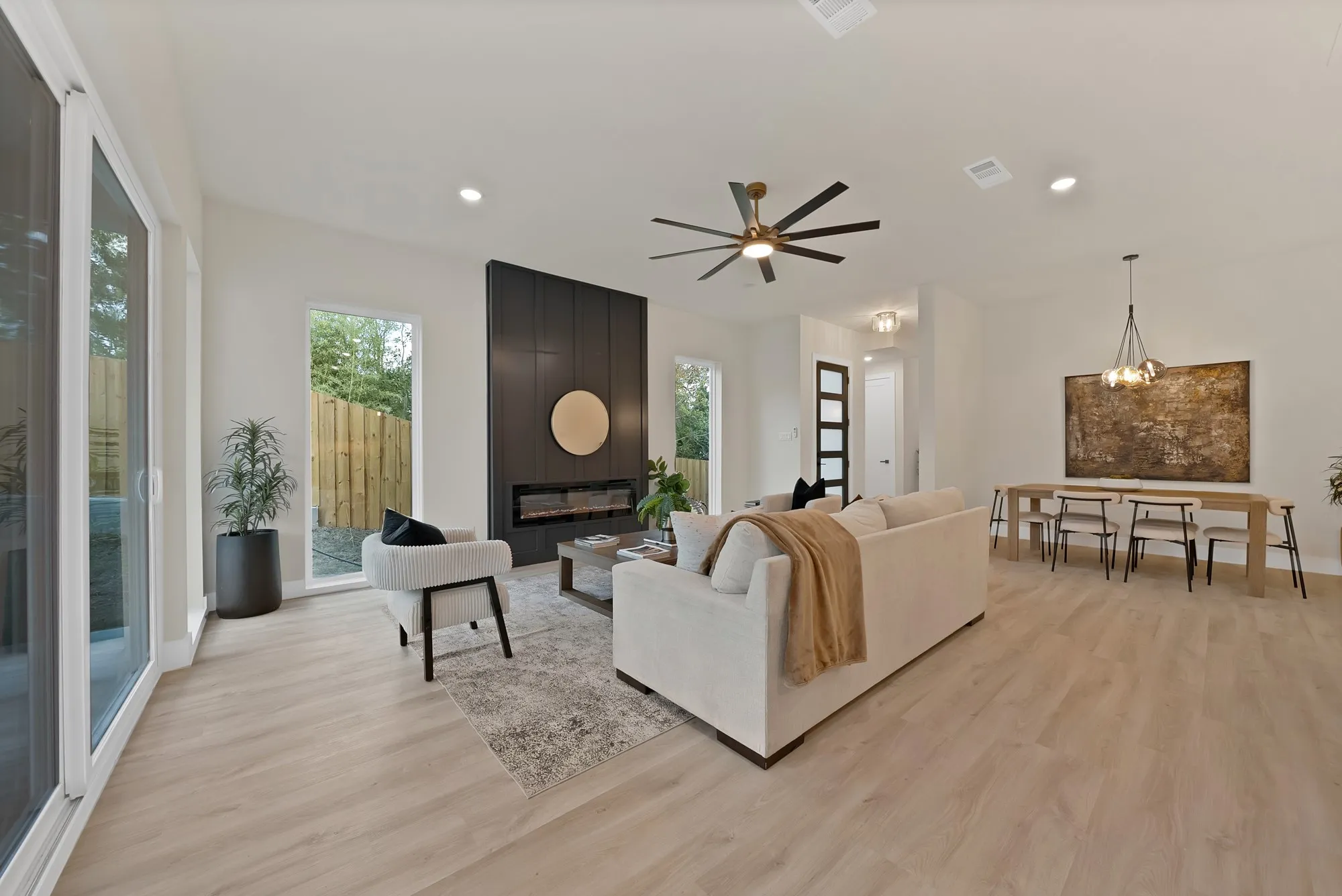Open-concept living space featuring wood-finish flooring, a contemporary fireplace, and a dining area with a modern chandelier