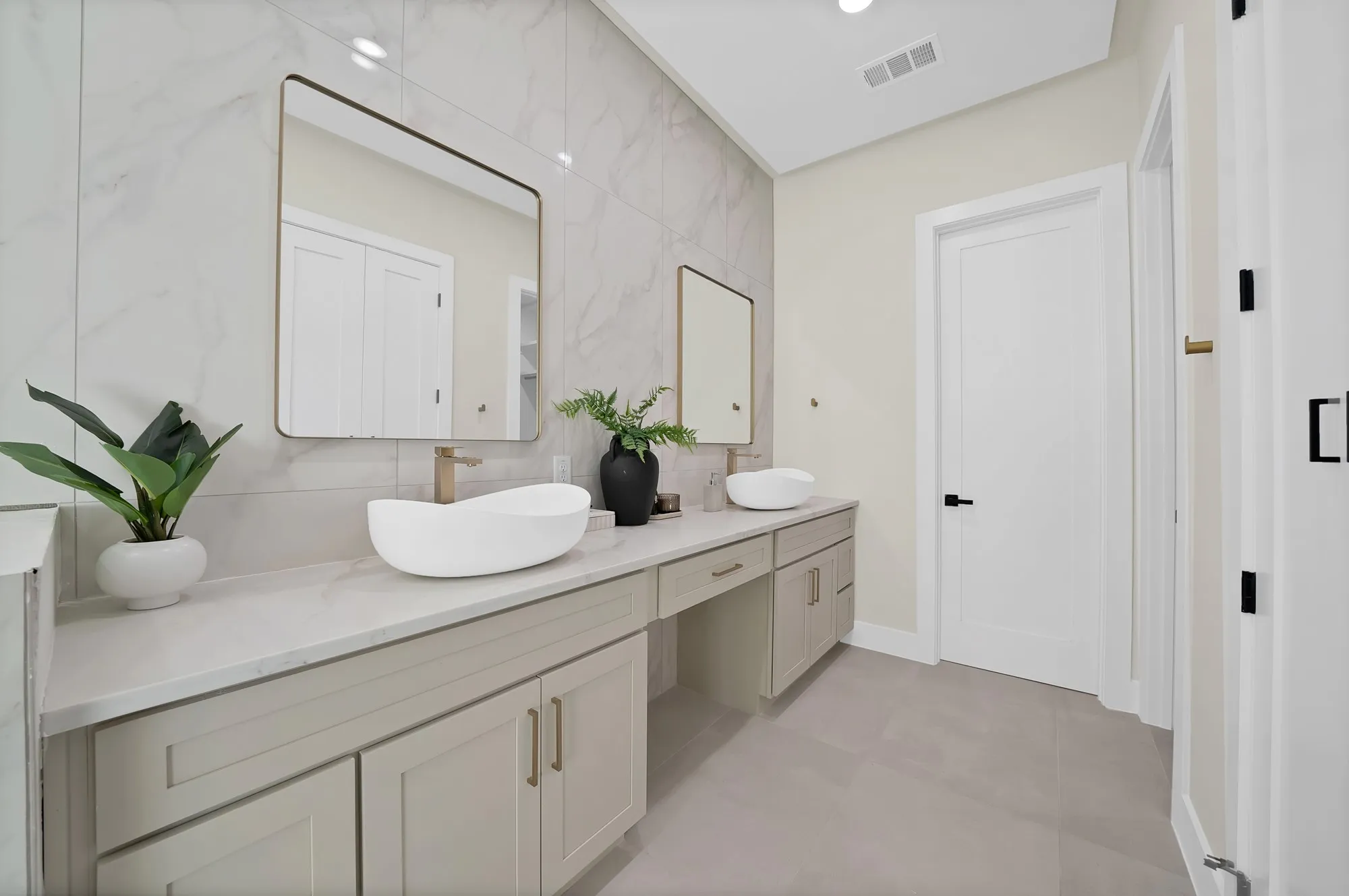 Dual vanity with vessel sinks, light gray cabinetry, and brass-finish hardware