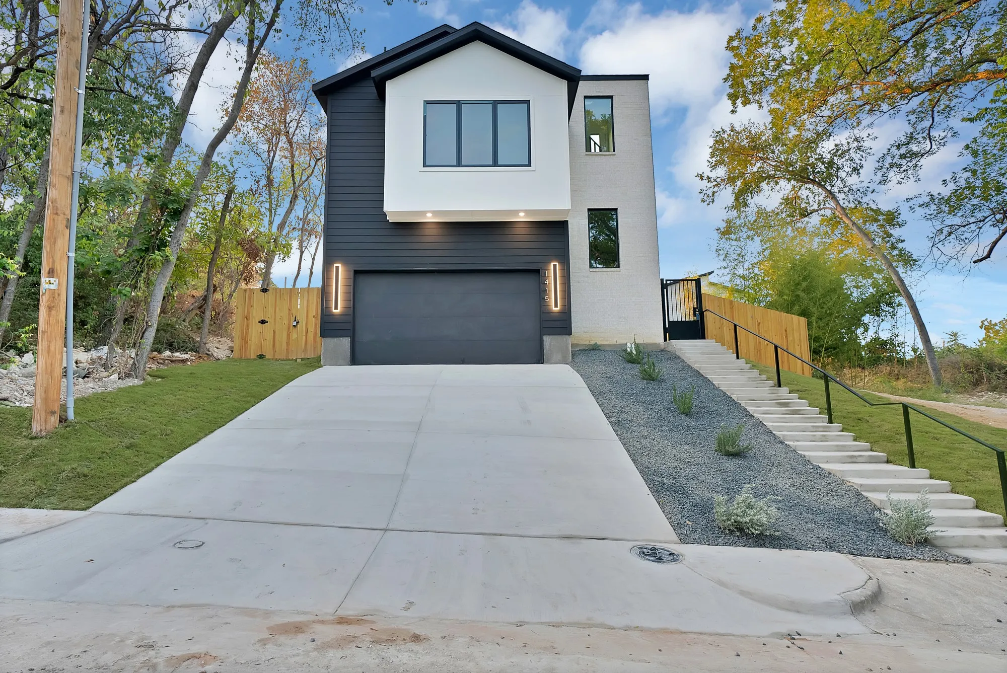 Modern exterior featuring dark siding, white stucco accents, and a large concrete driveway
