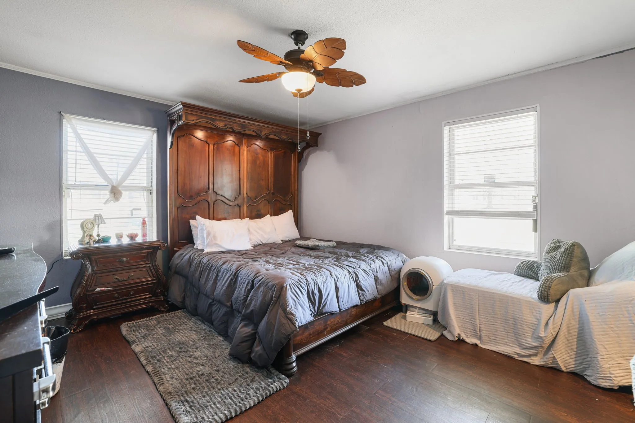 Wood-finish flooring throughout, multiple windows with blinds, and a ceiling fan with integrated lighting