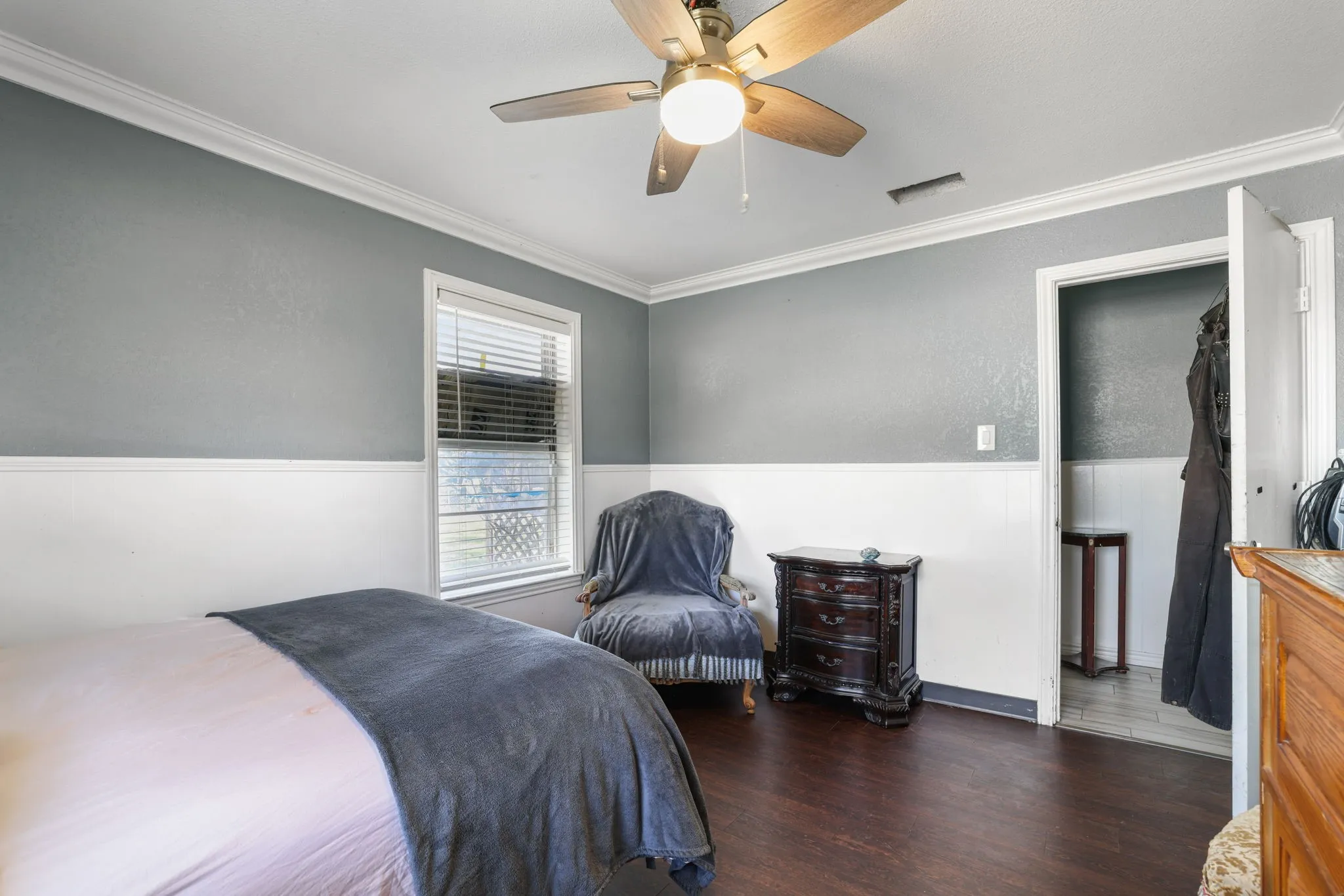 Wood-finish flooring, crown molding, two-tone wall treatment, ceiling fan with light, and a window with blinds