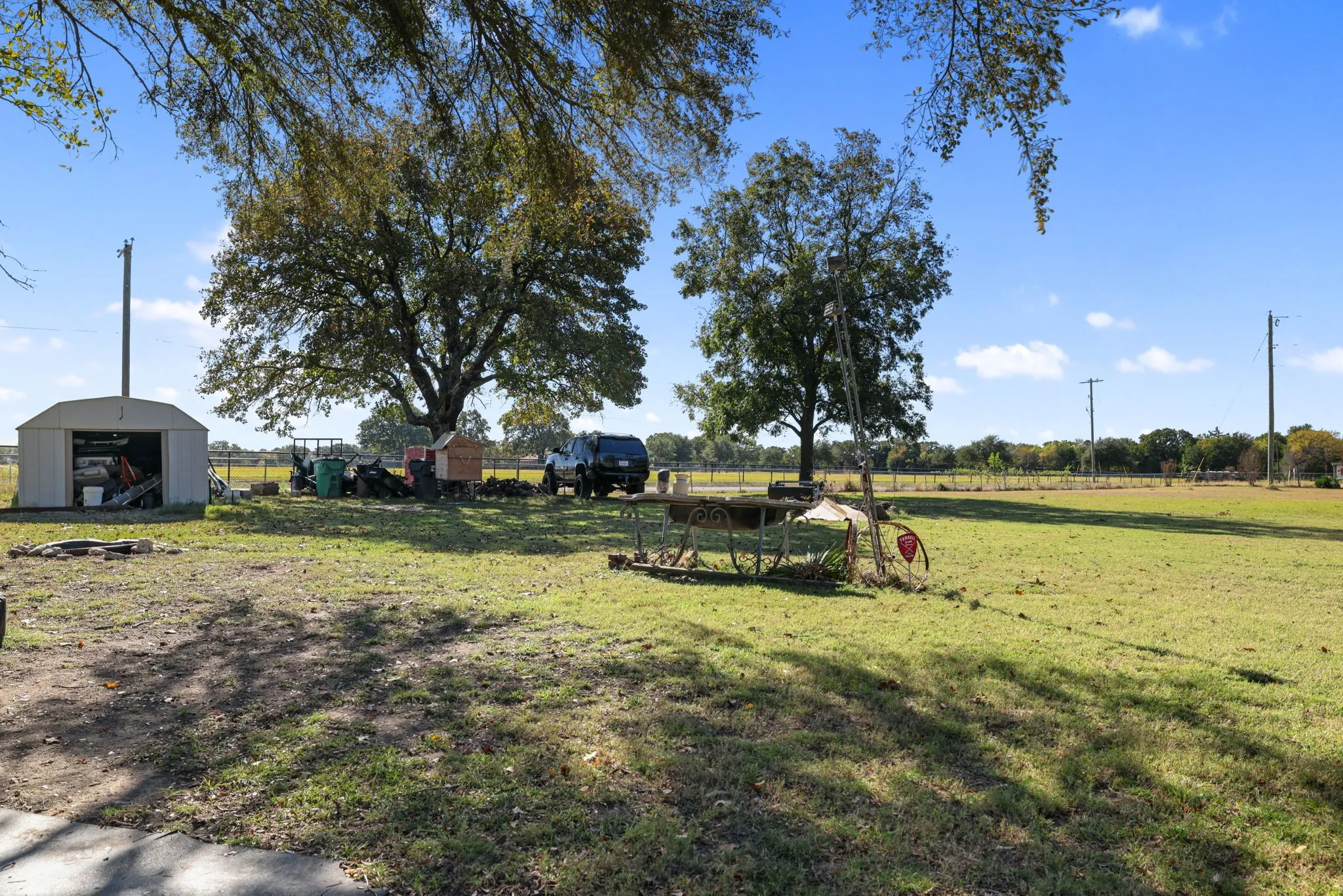 Expansive grassy area featuring mature trees and a metal outbuilding